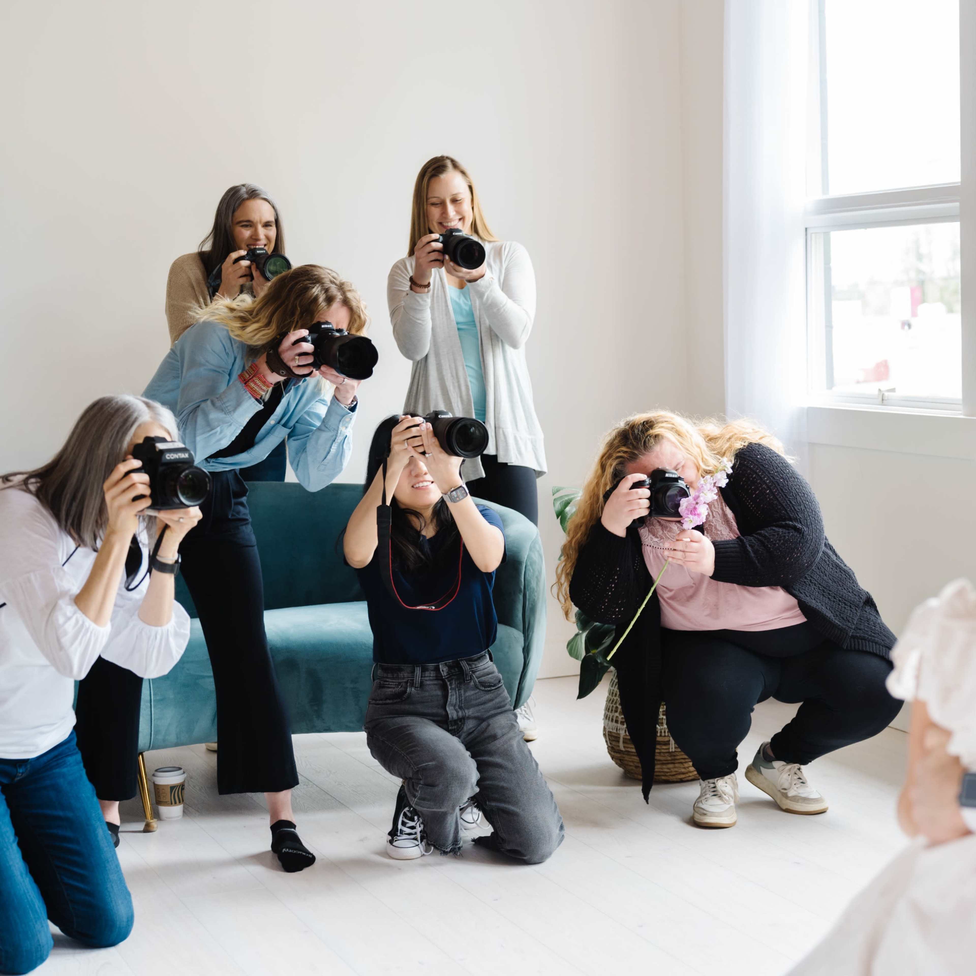 A group of photographers is capturing images of a couple posing in a well-lit indoor space.