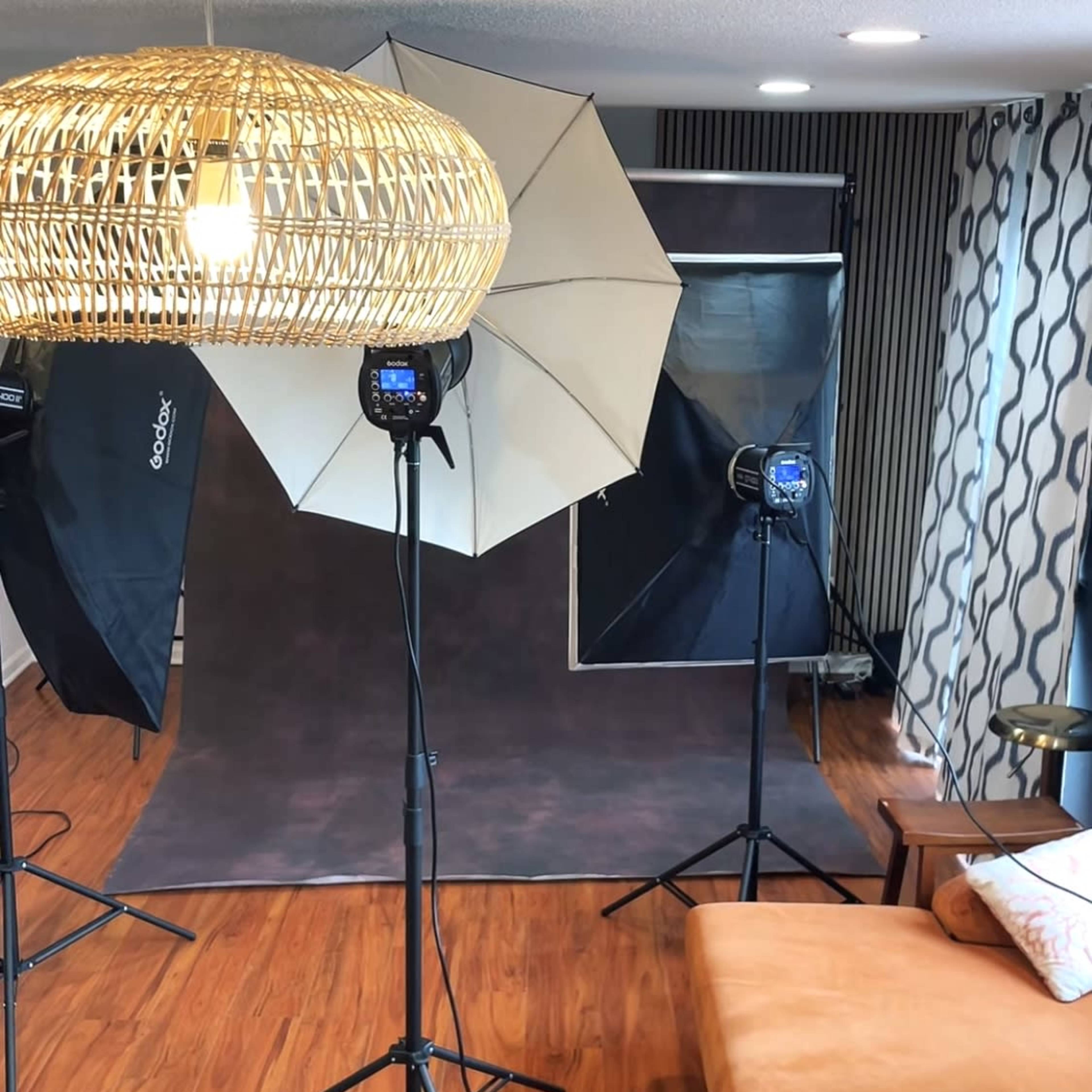 A photography studio setup with lighting equipment, a backdrop, and a brown sofa.