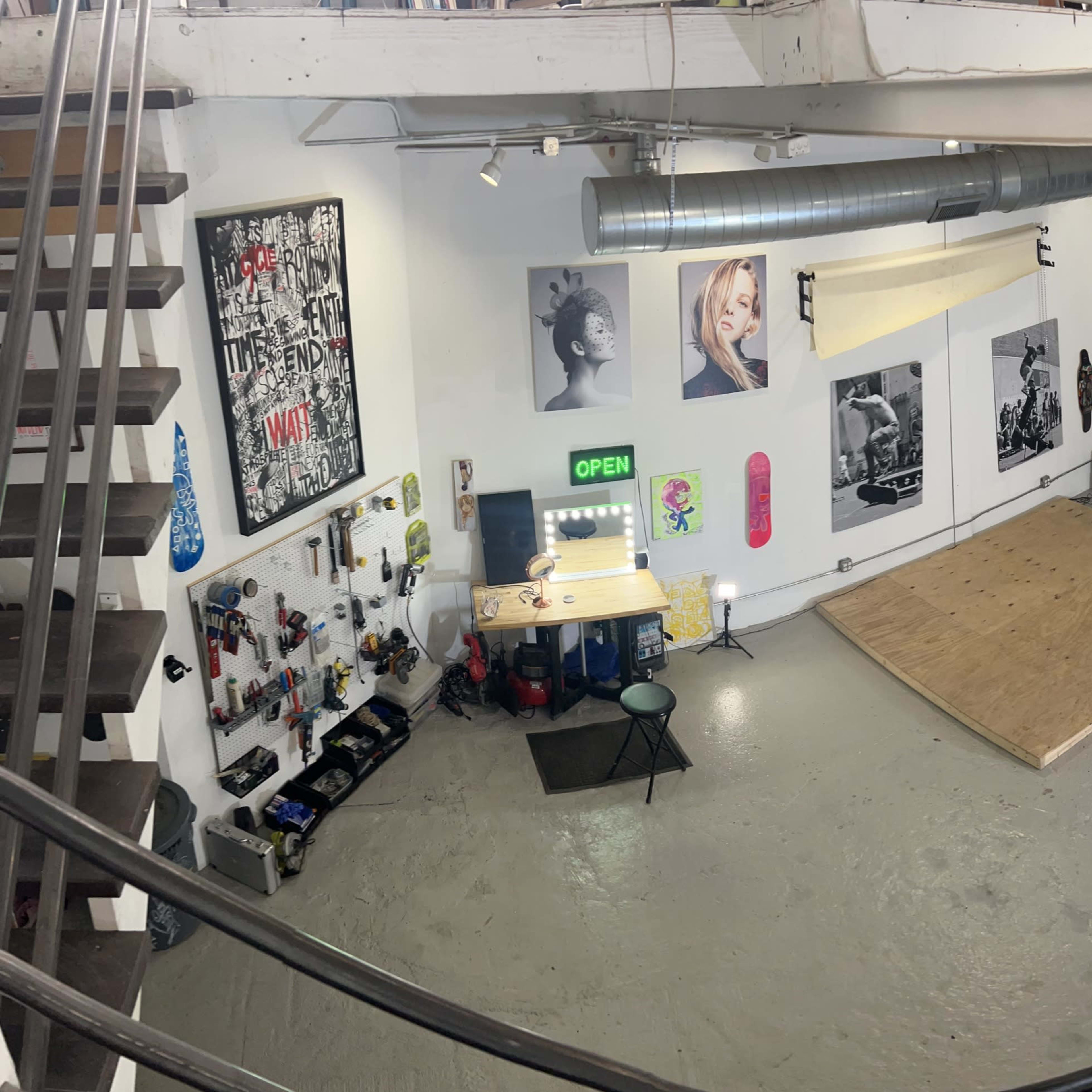 A spacious art studio featuring a skateboard ramp, various artworks on the walls, and a workbench with tools and equipment.