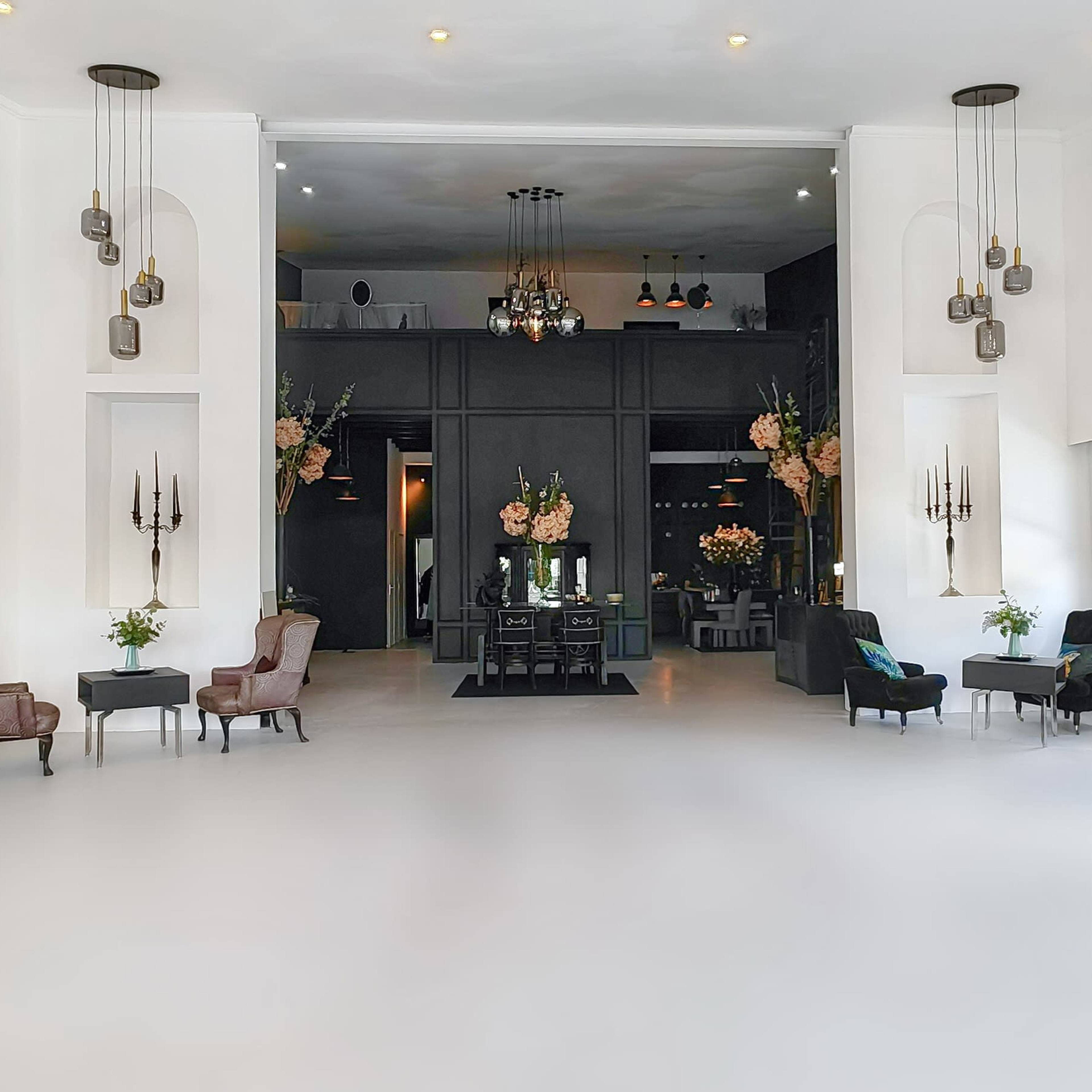 A spacious, well-lit interior featuring elegant furniture, floral arrangements, and decorative shelves in a modern setting.