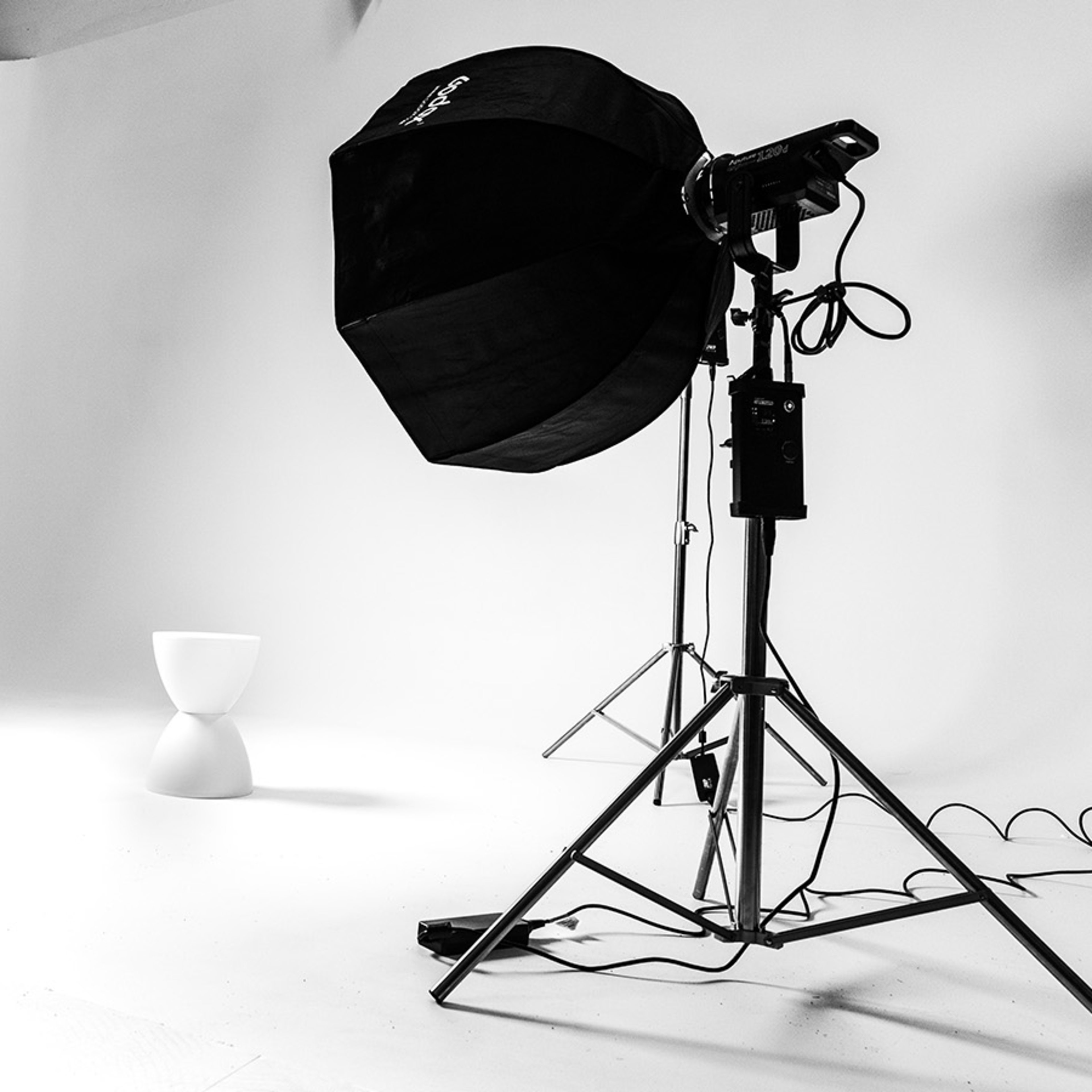 A photography studio with two light sources positioned on either side of a minimalist white pedestal.