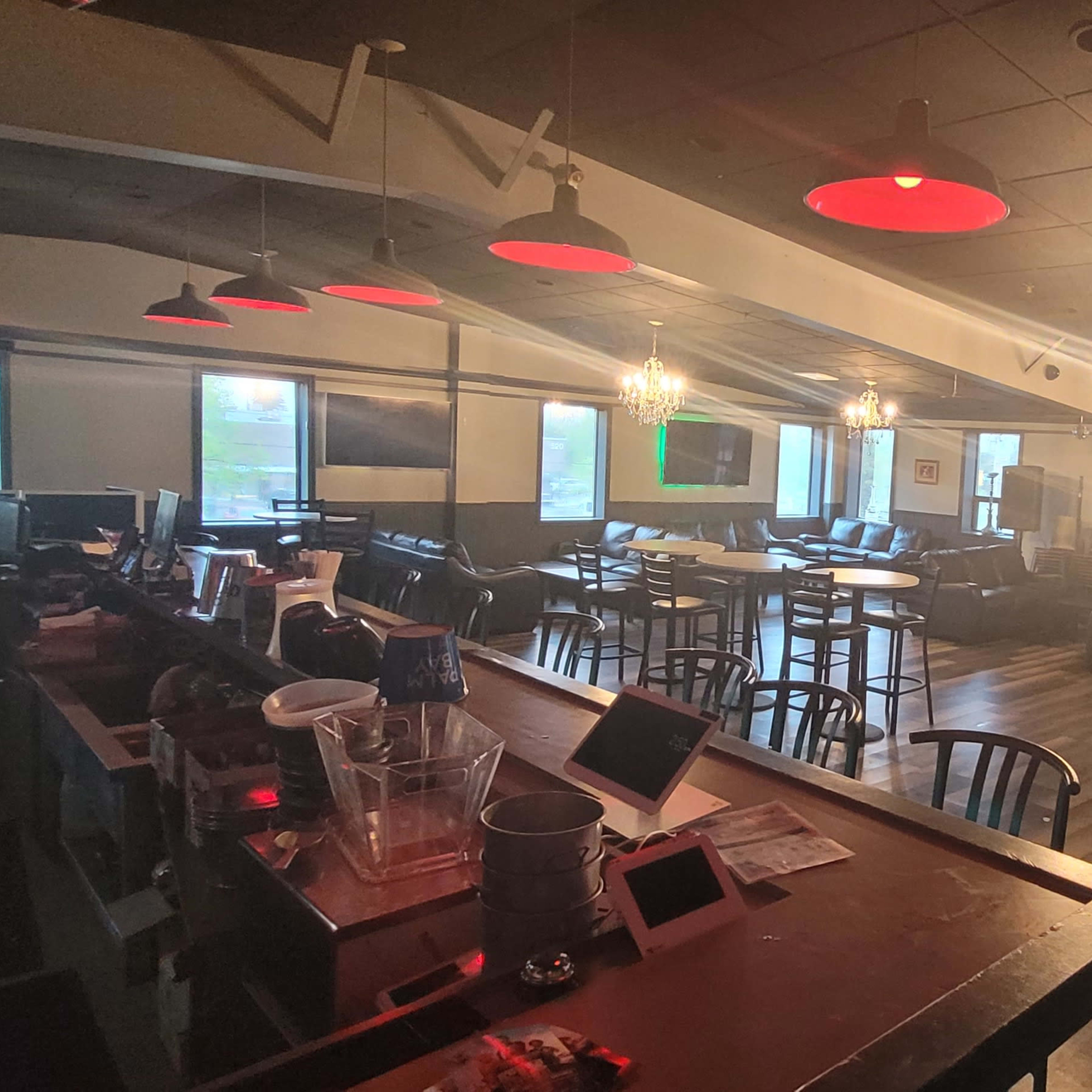 A dimly lit cafe or lounge with leather seating, tabletop games, and a bar area.