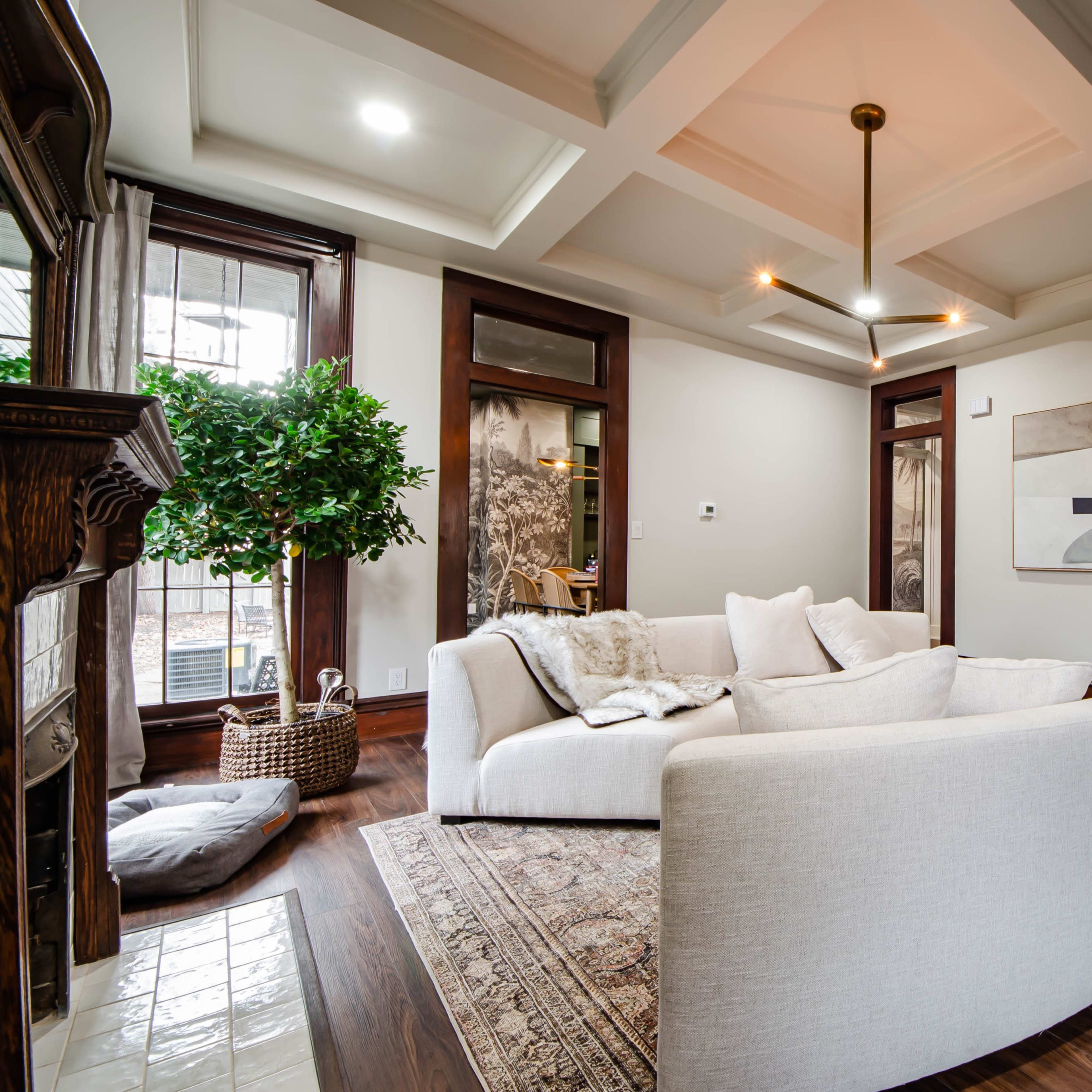 A light-colored sectional sofa in a modern living room with wooden floors, a large artwork on the wall, and a potted plant in the corner.