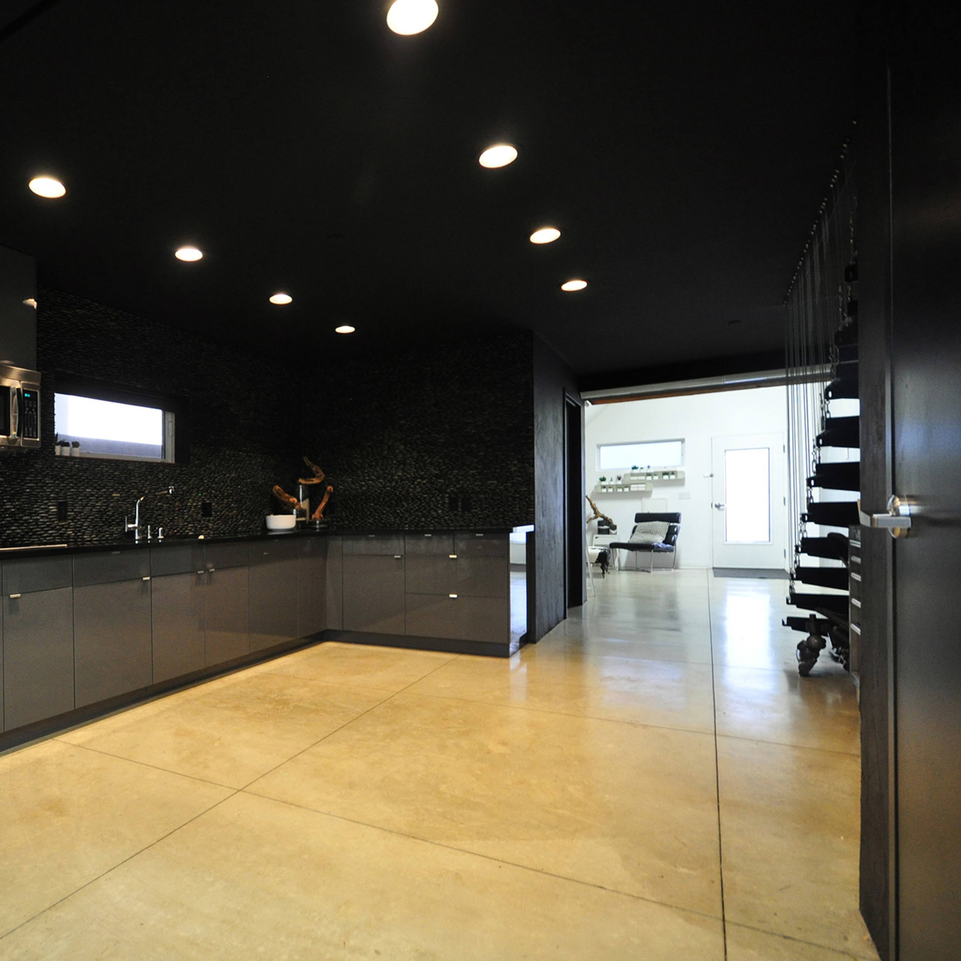 A modern kitchen features sleek gray cabinetry, minimalist design, and a large counter space with stainless steel appliances.