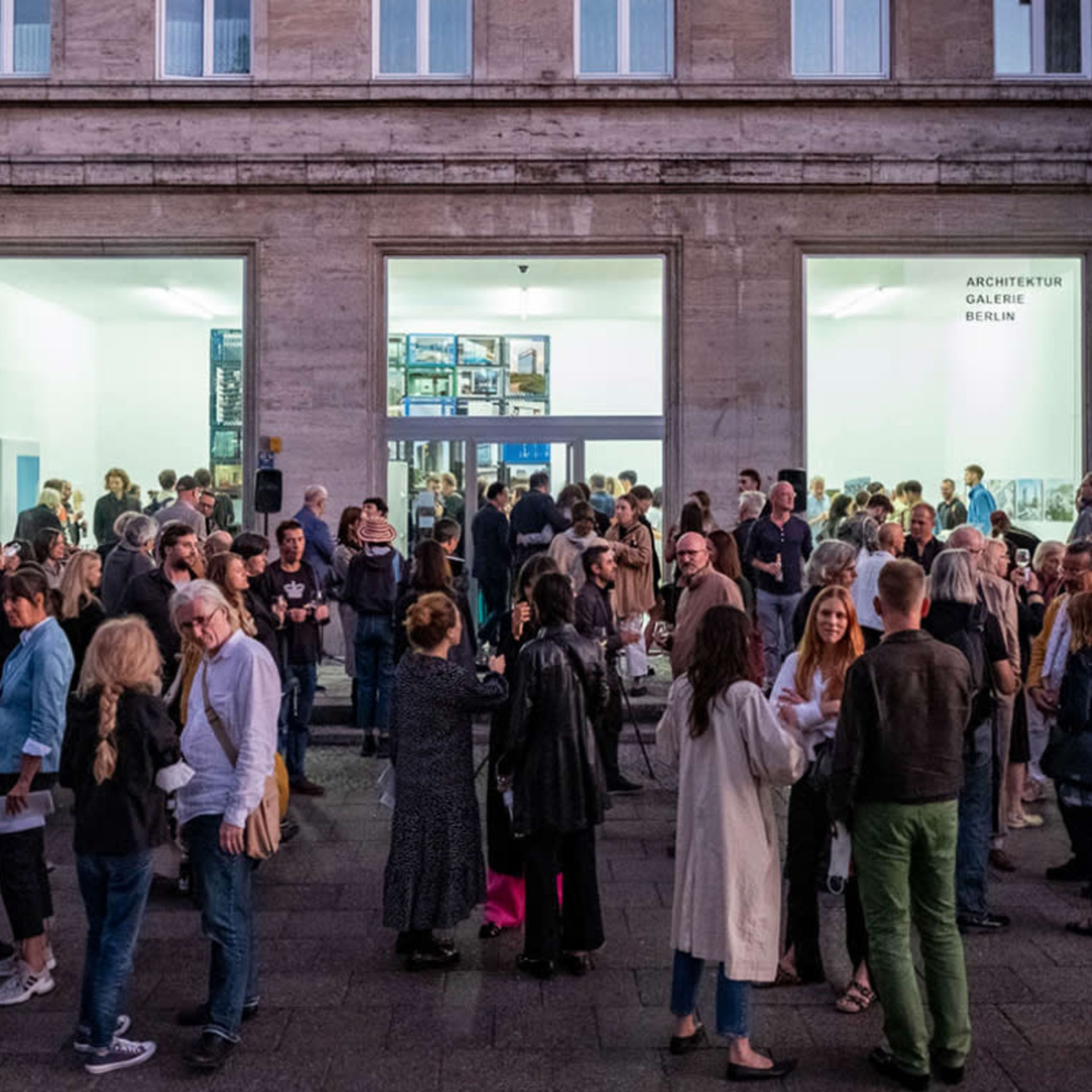 A large crowd gathers outside the Architecture Gallery in Berlin during an evening event.