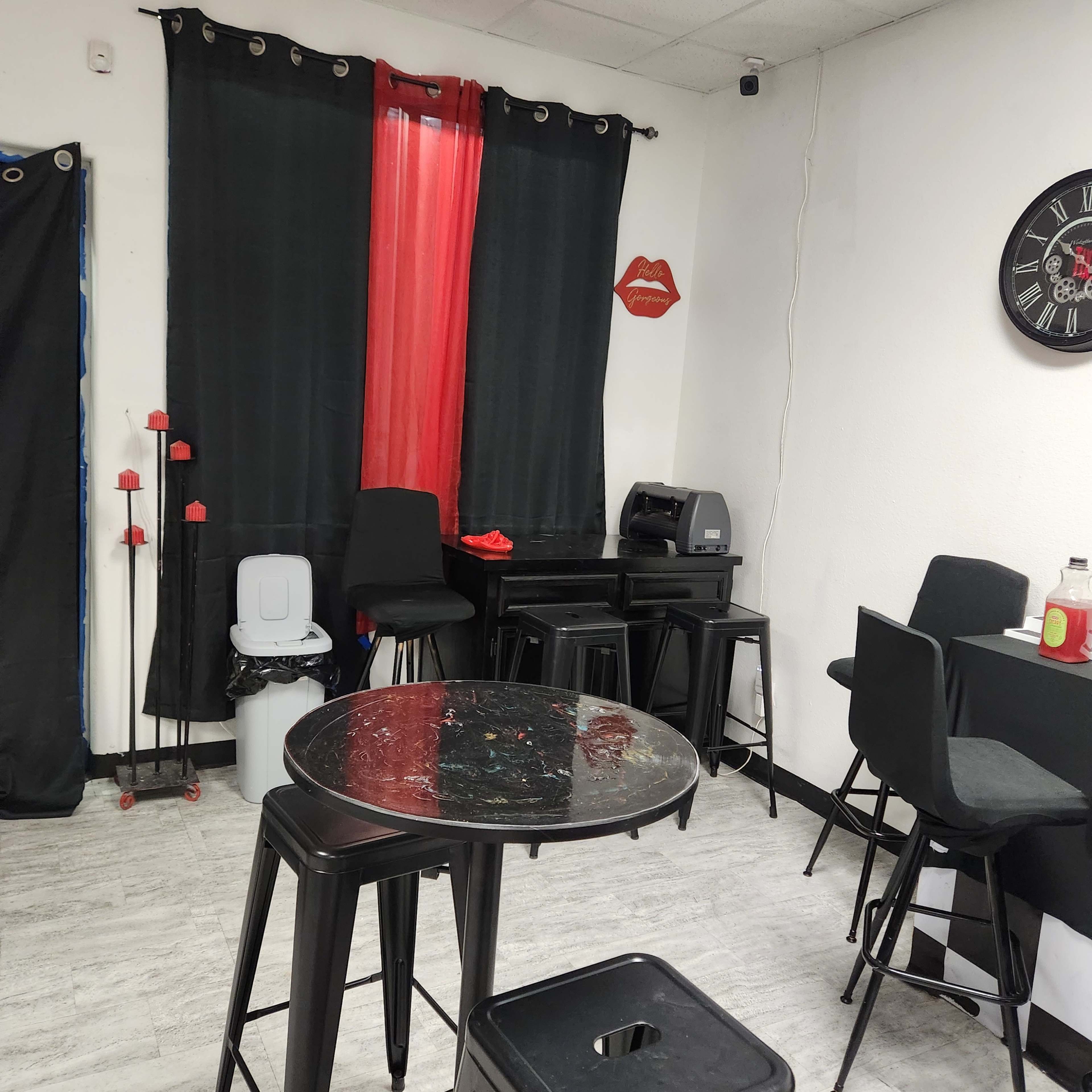 A small, modern room with black tables and chairs, red accents, and a clock on the wall.