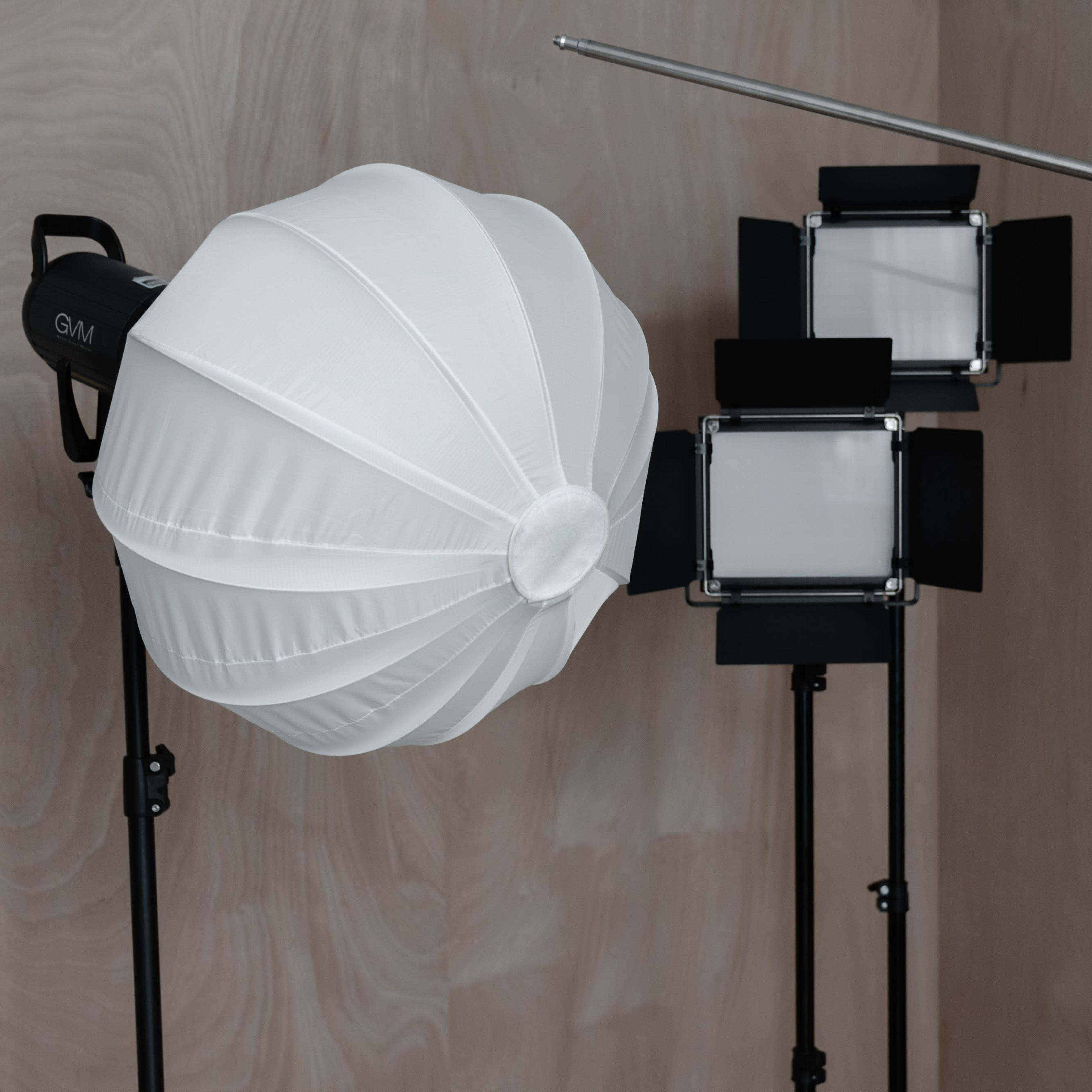 Various photography equipment, including softboxes and lighting stands, arranged against a wooden background.