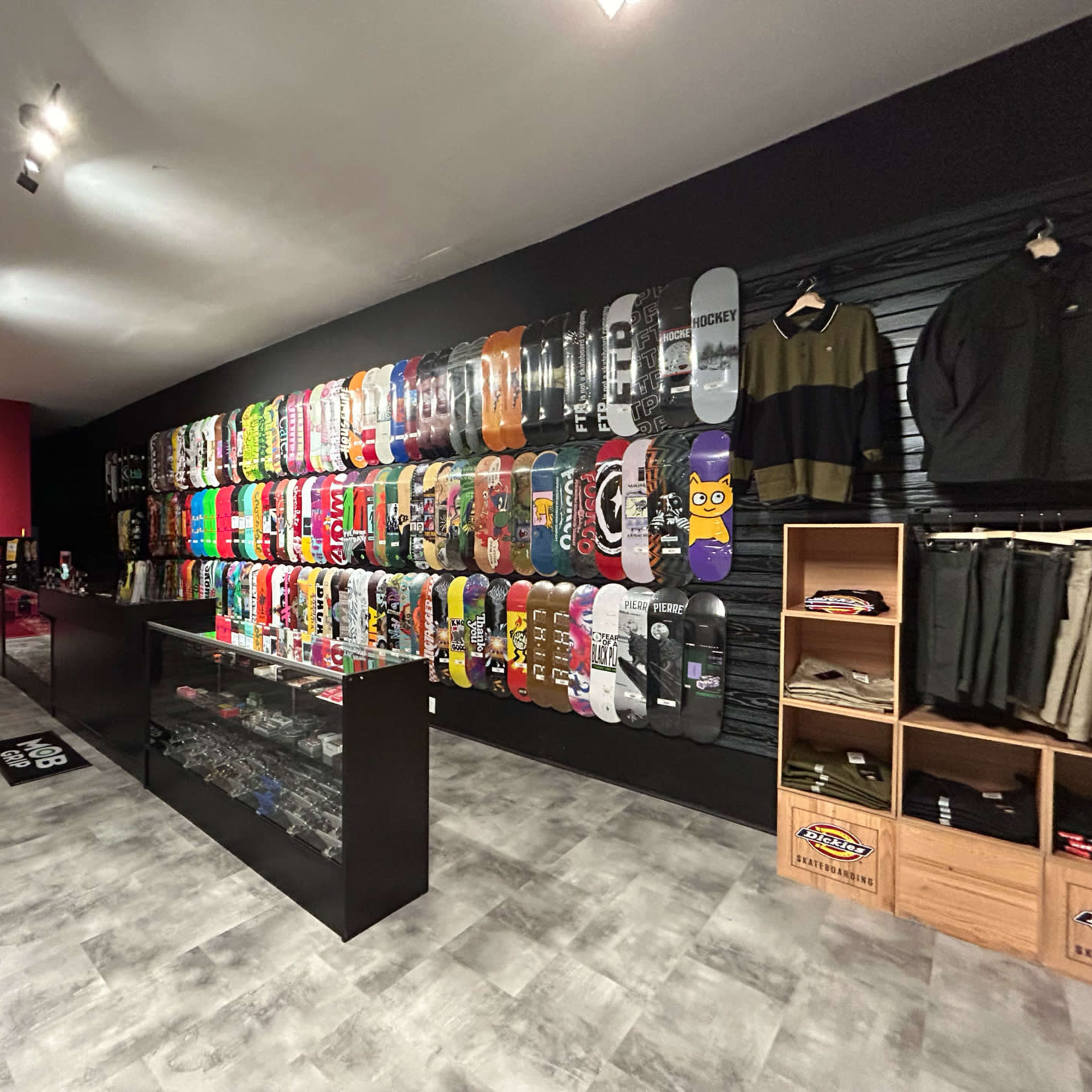 A skate shop interior with a wall of colorful skateboards displayed alongside apparel and accessories on shelves.