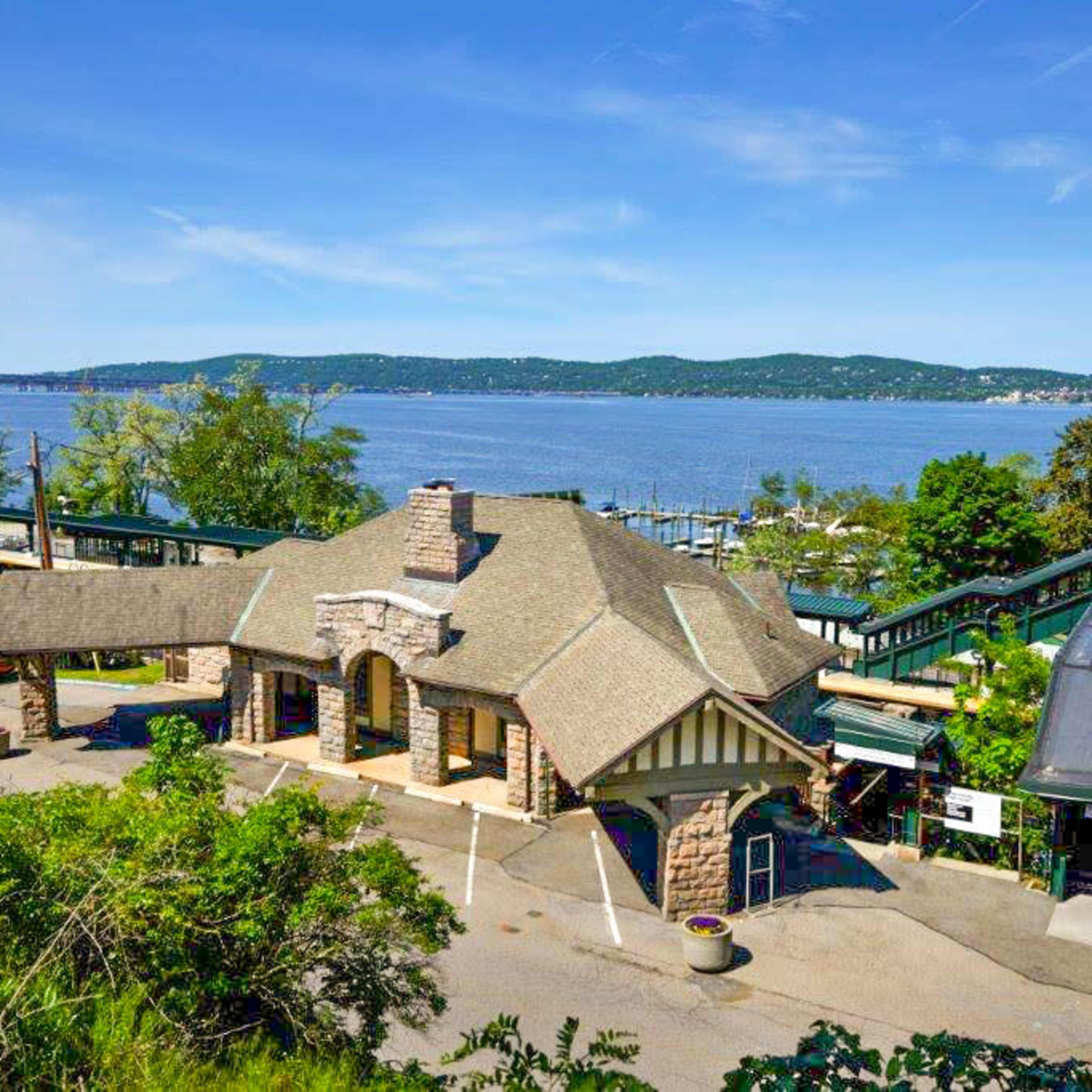 A waterfront train station with a stone building and a scenic view of the river and hills in the background.