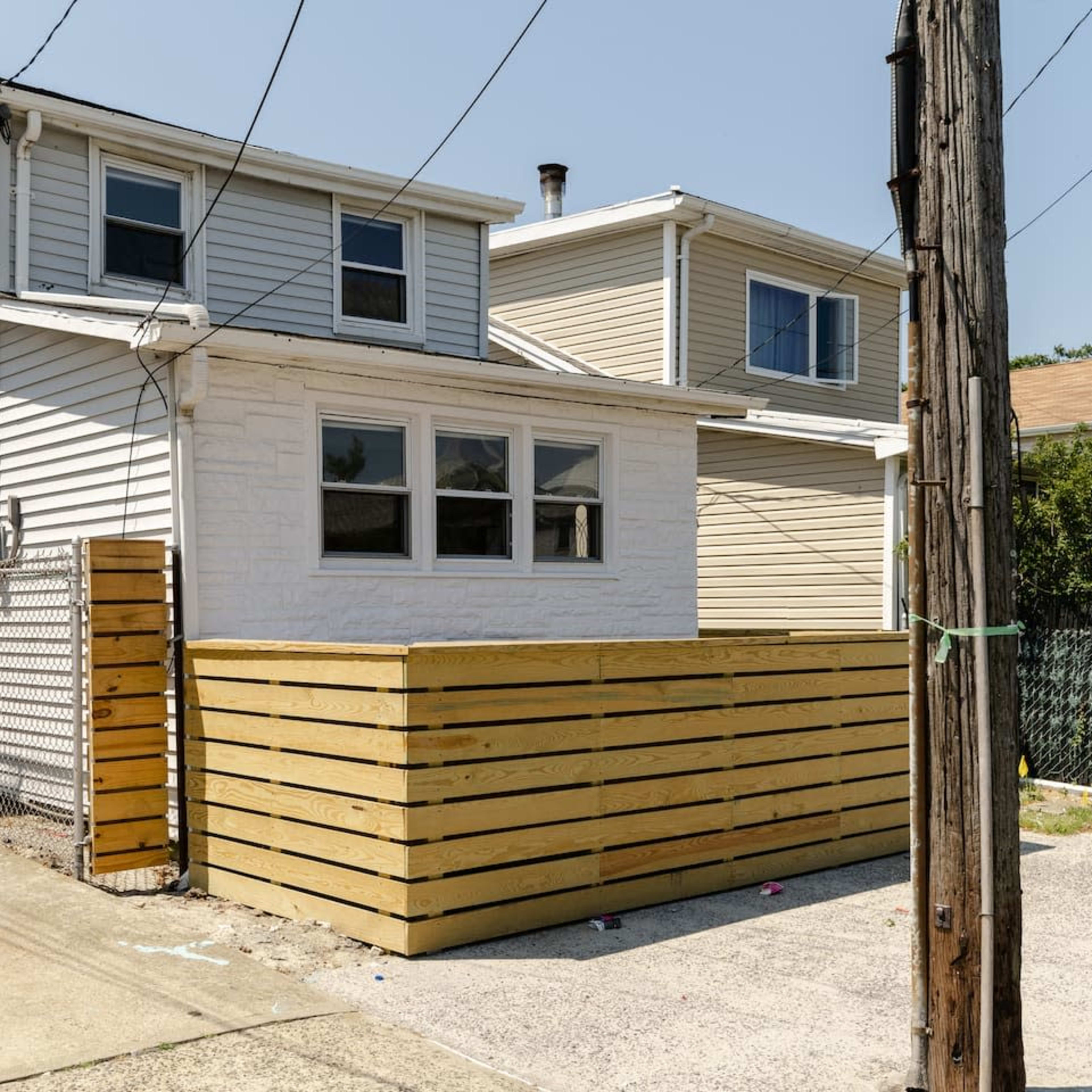 A residential building with a newly constructed wooden fence and a driveway beside it.