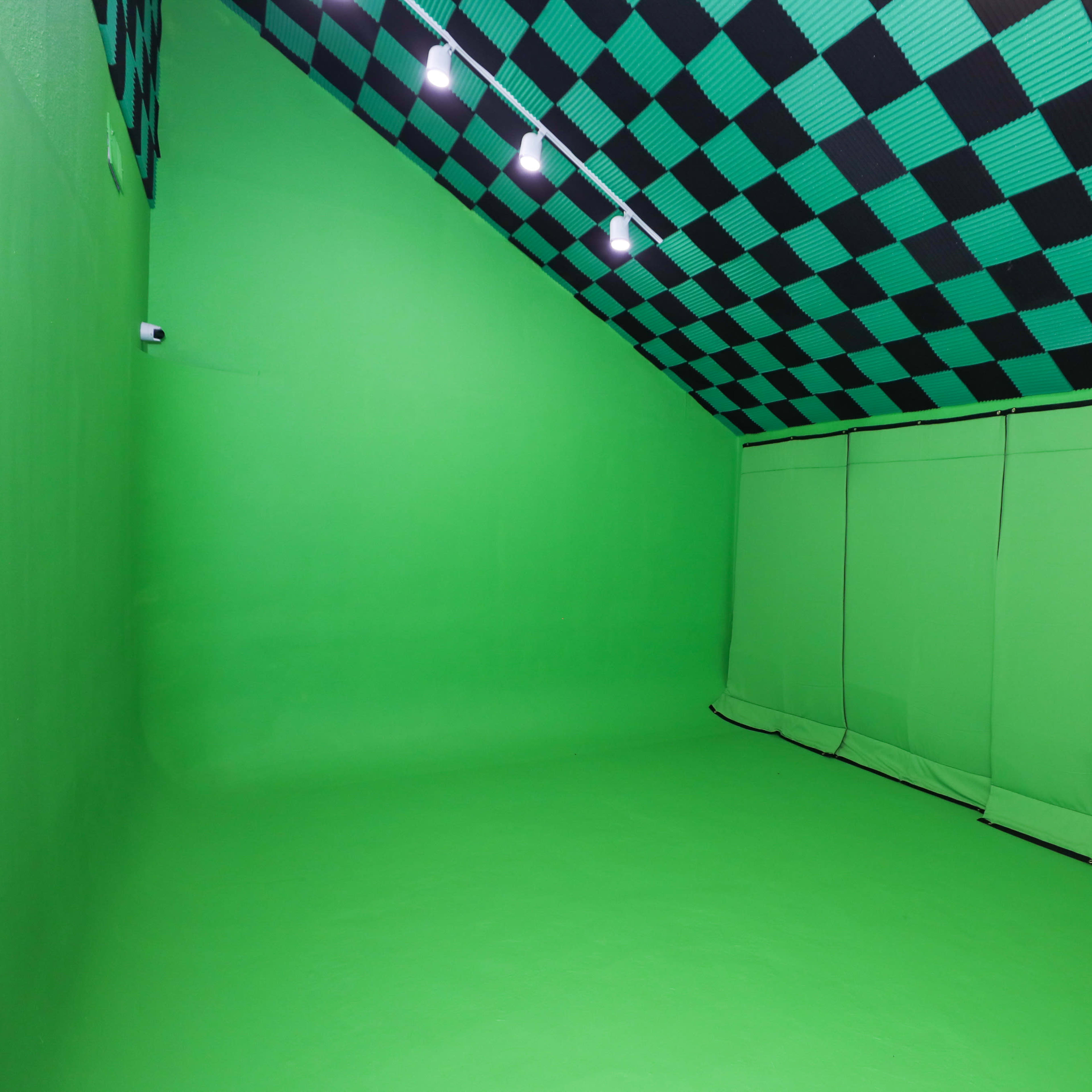 A green screen studio with a black and green checkered ceiling and smooth green walls and floor.