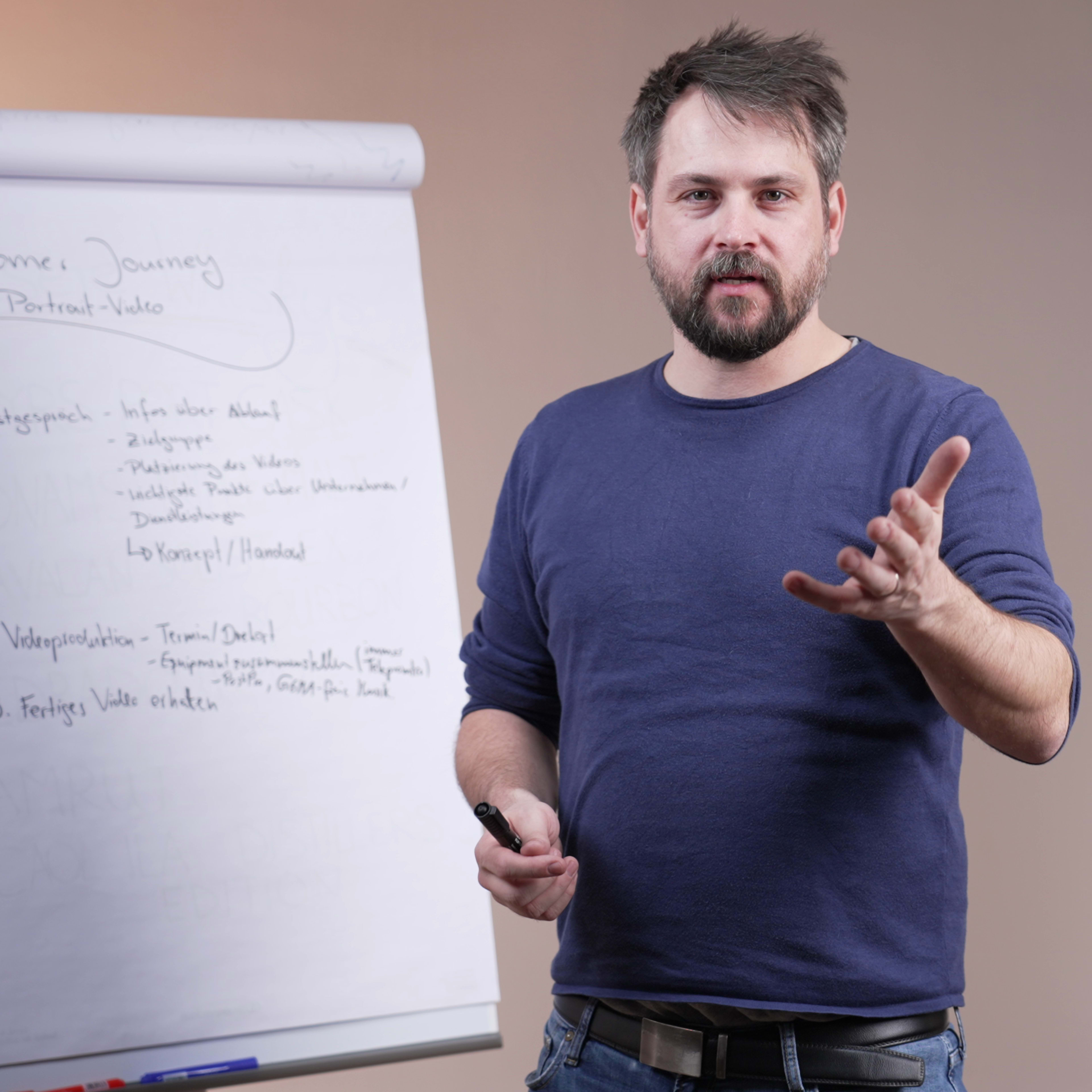 A man stands in front of a whiteboard, gesturing as he presents information about the customer journey.
