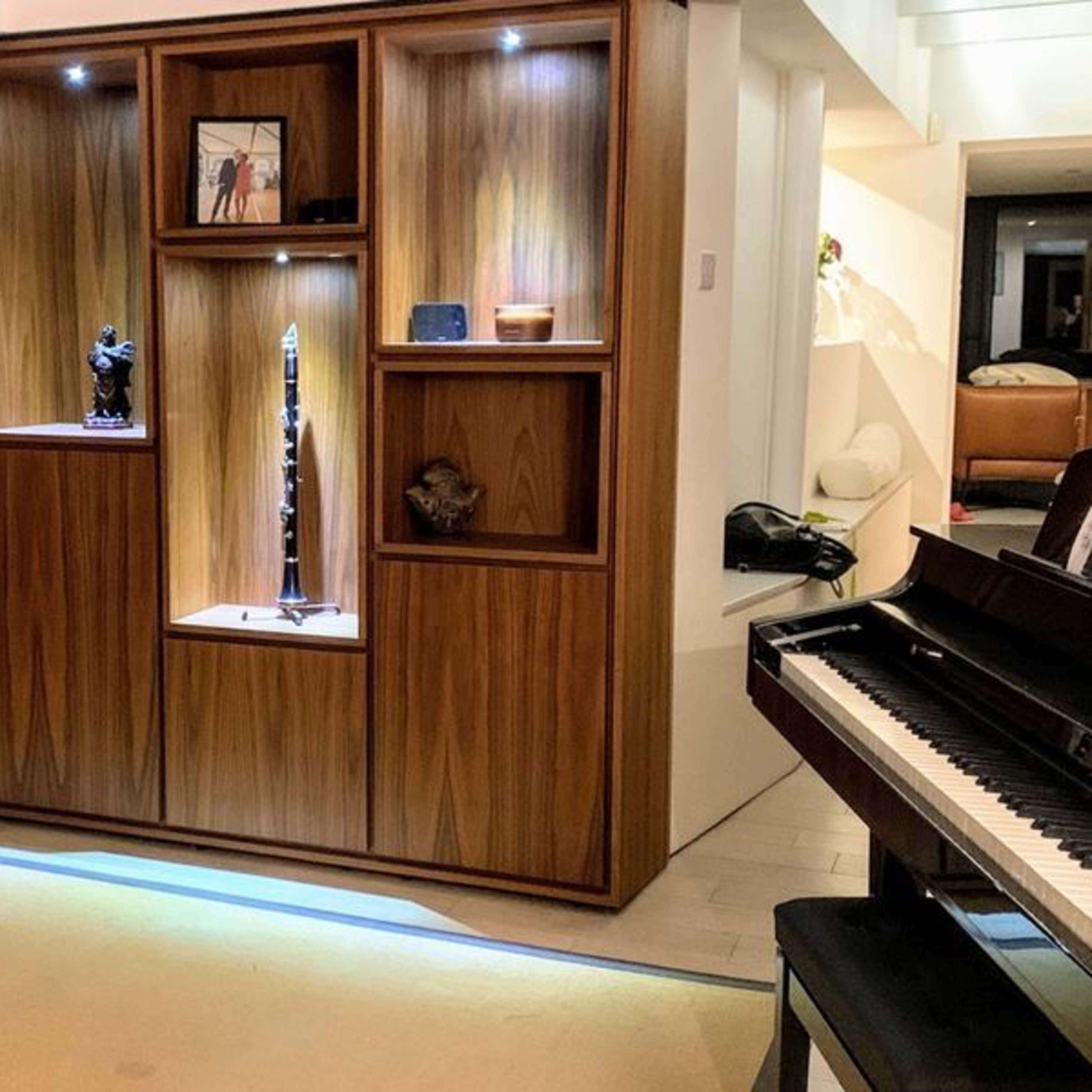 A modern interior space featuring a wooden display cabinet with various decorative items and a piano in the foreground.