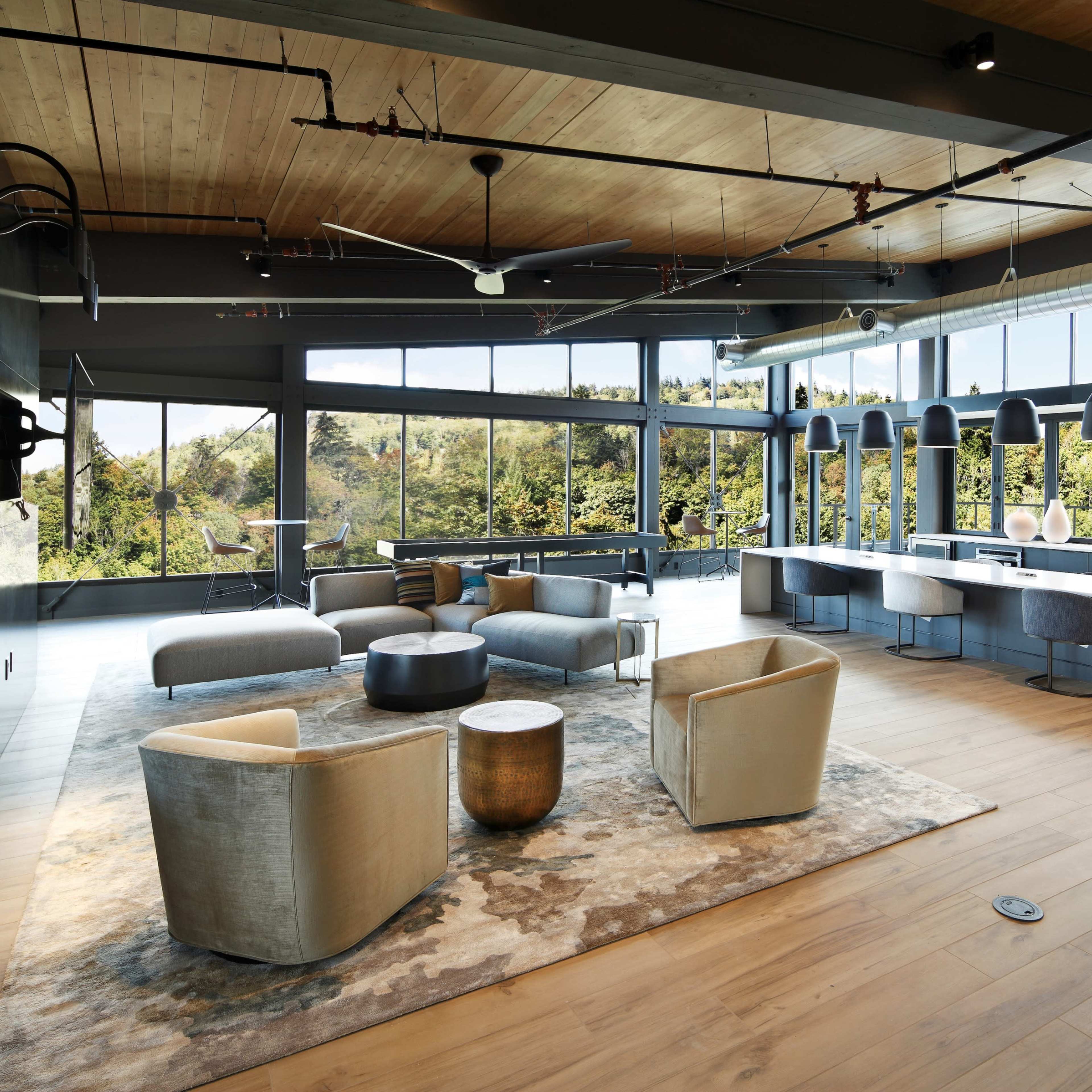 A spacious interior features modern seating arrangements and large windows overlooking a natural landscape.