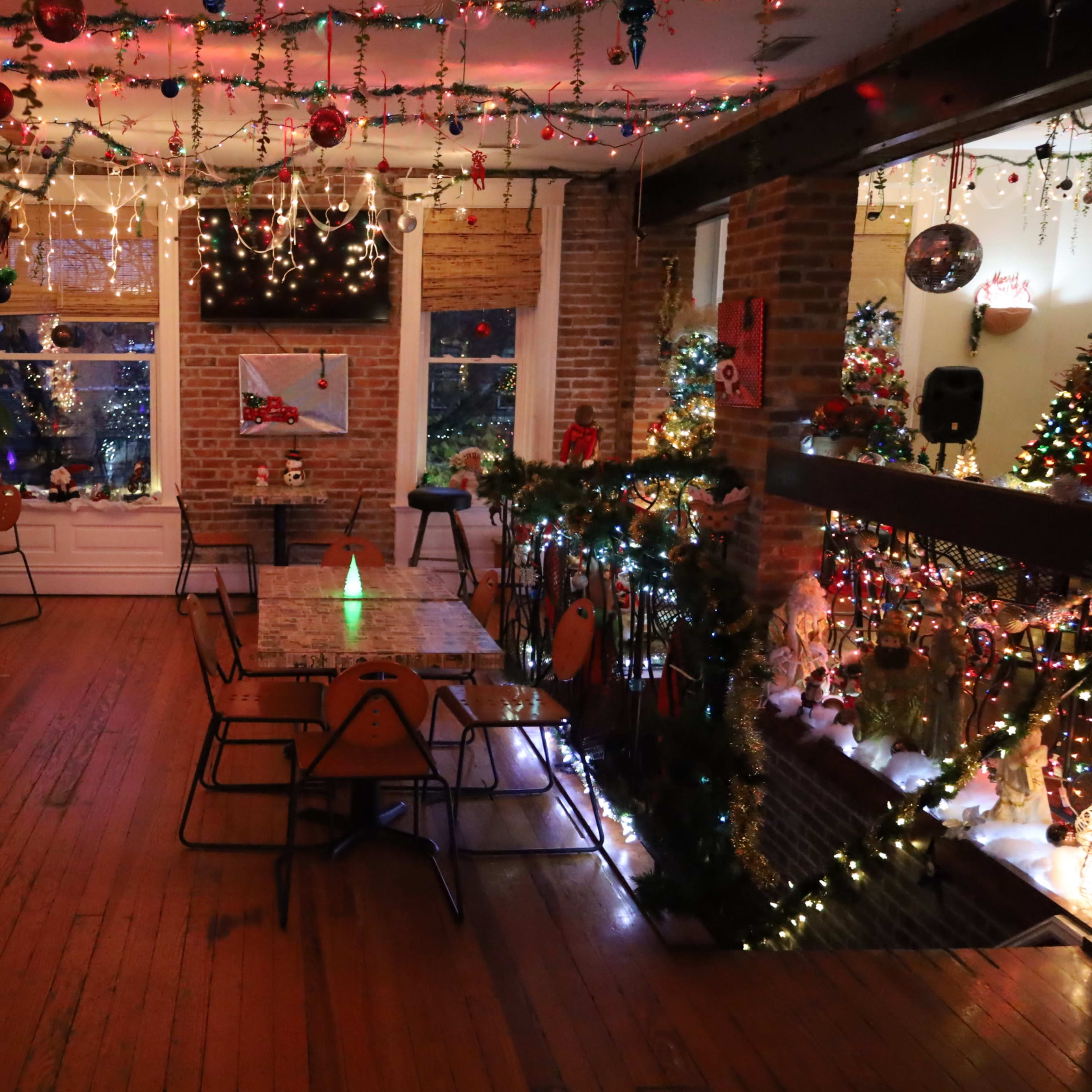 The room features wooden floors, several tables, and walls adorned with colorful holiday lights and decorations, creating a festive atmosphere.