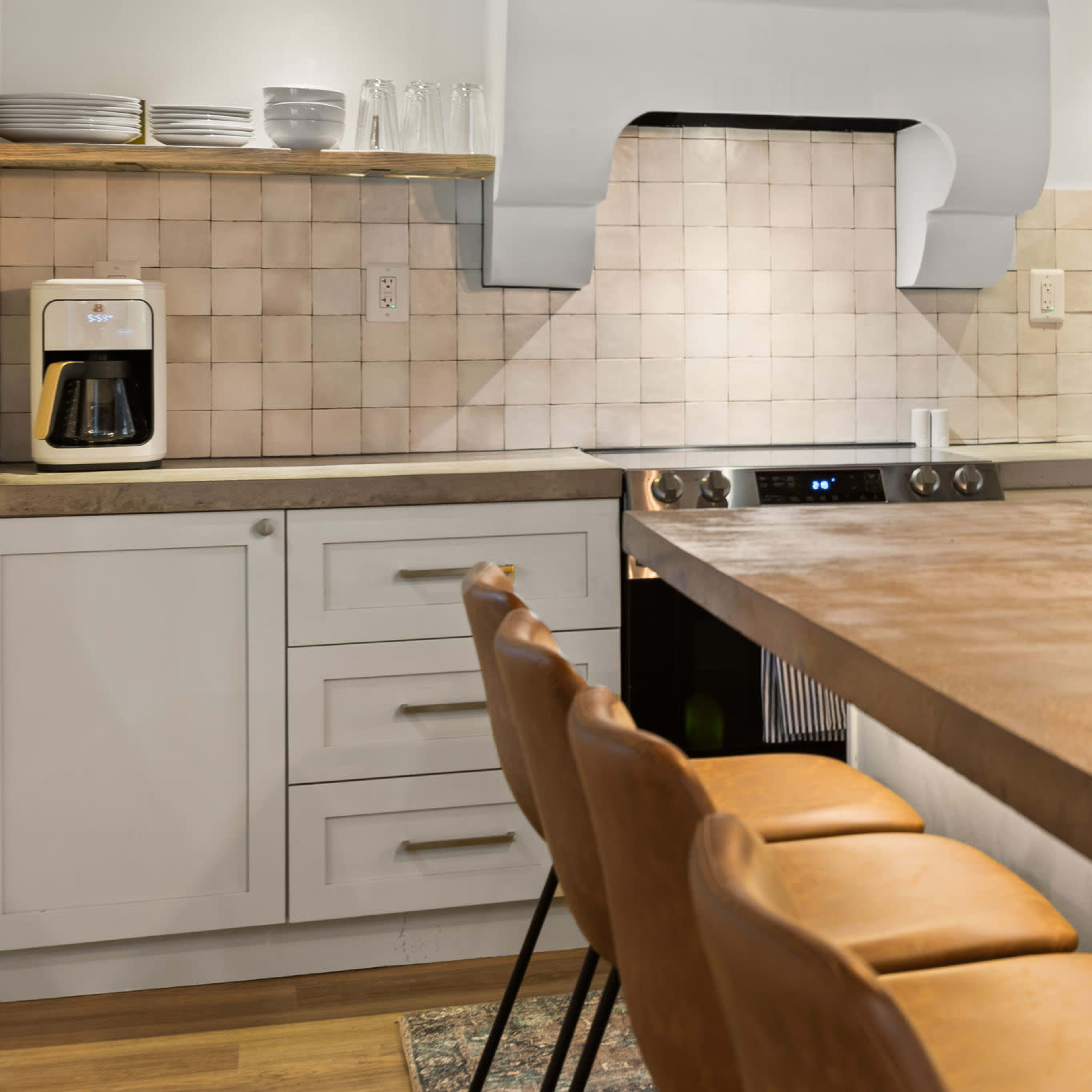 A modern kitchen with a copper countertop, beige tile backsplash, white cabinetry, a stainless steel stove, and a retro-style refrigerator.