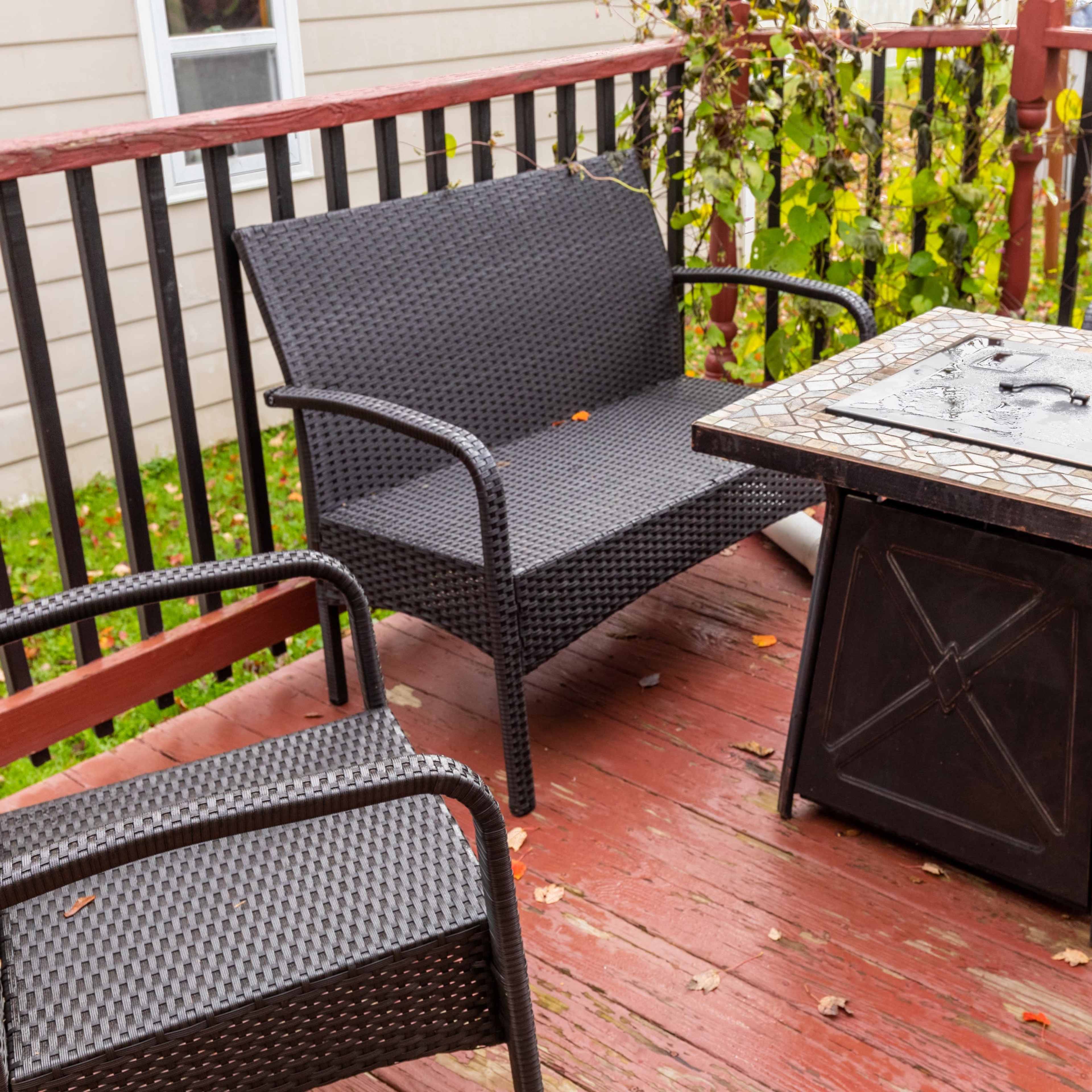 A wooden deck featuring a table with a decorative top and four wicker chairs arranged around it.