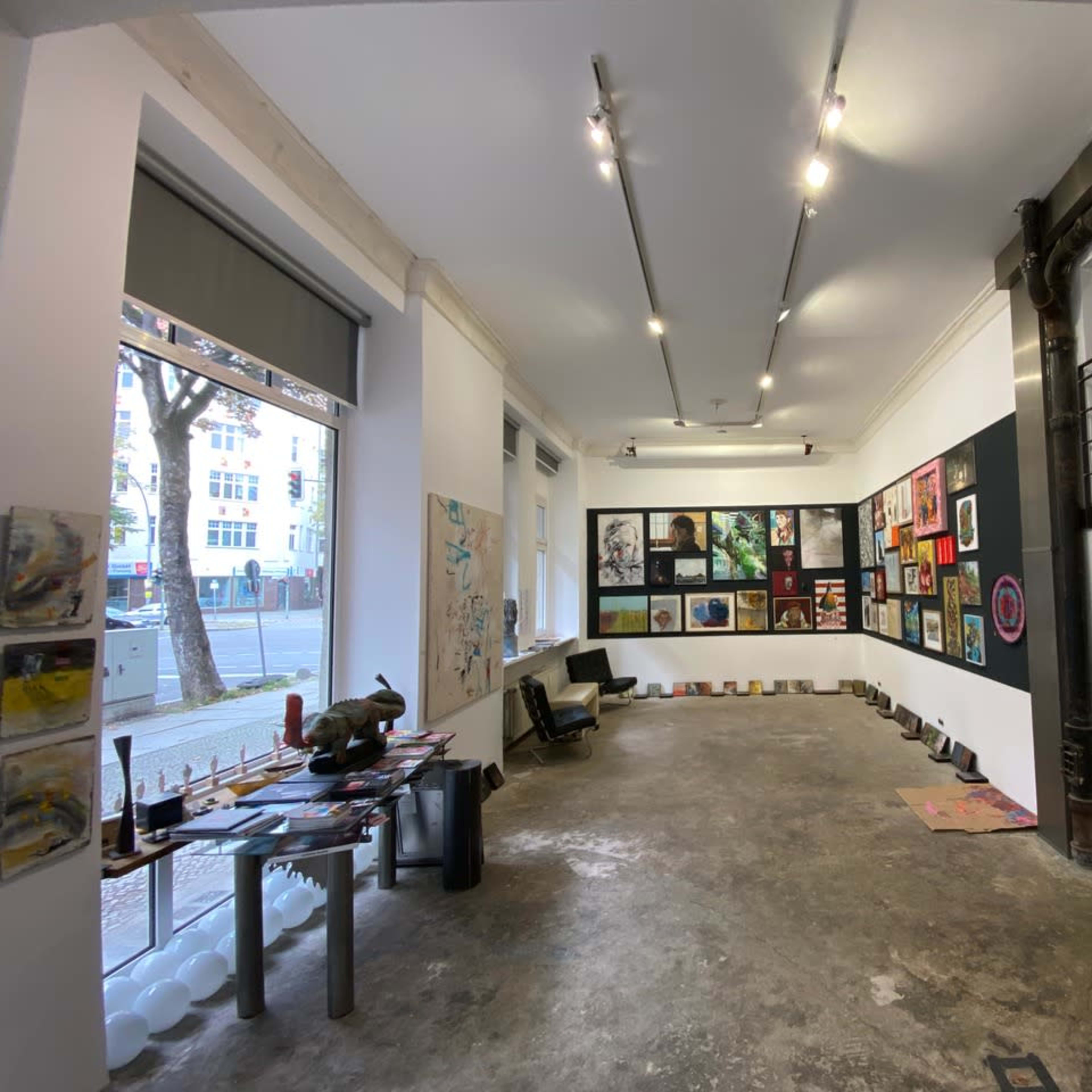 A spacious art gallery with various artworks displayed on the walls and sculptures positioned on the floor.