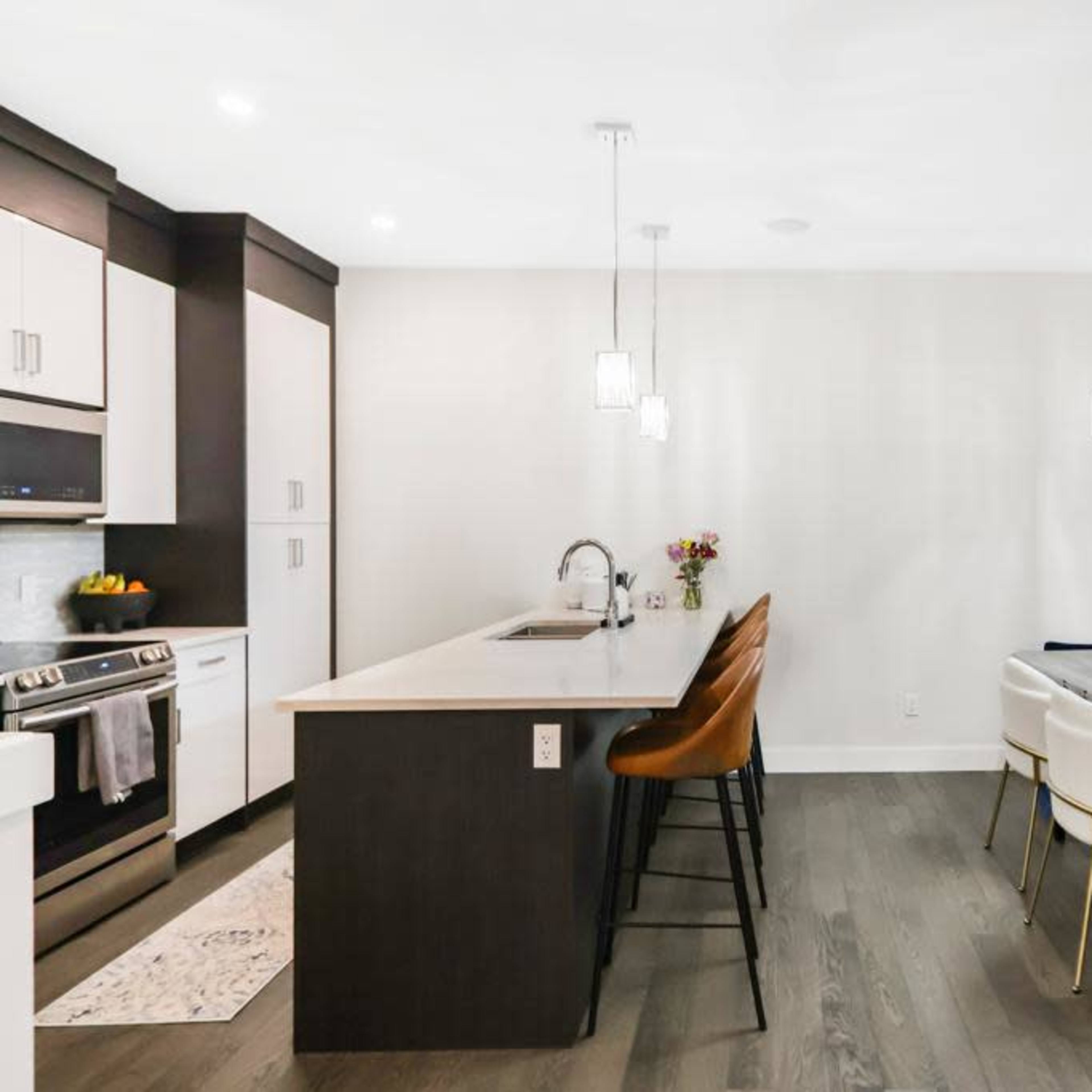 A modern kitchen and dining area featuring a central island with seating, a formal dining table, and pendant lighting.