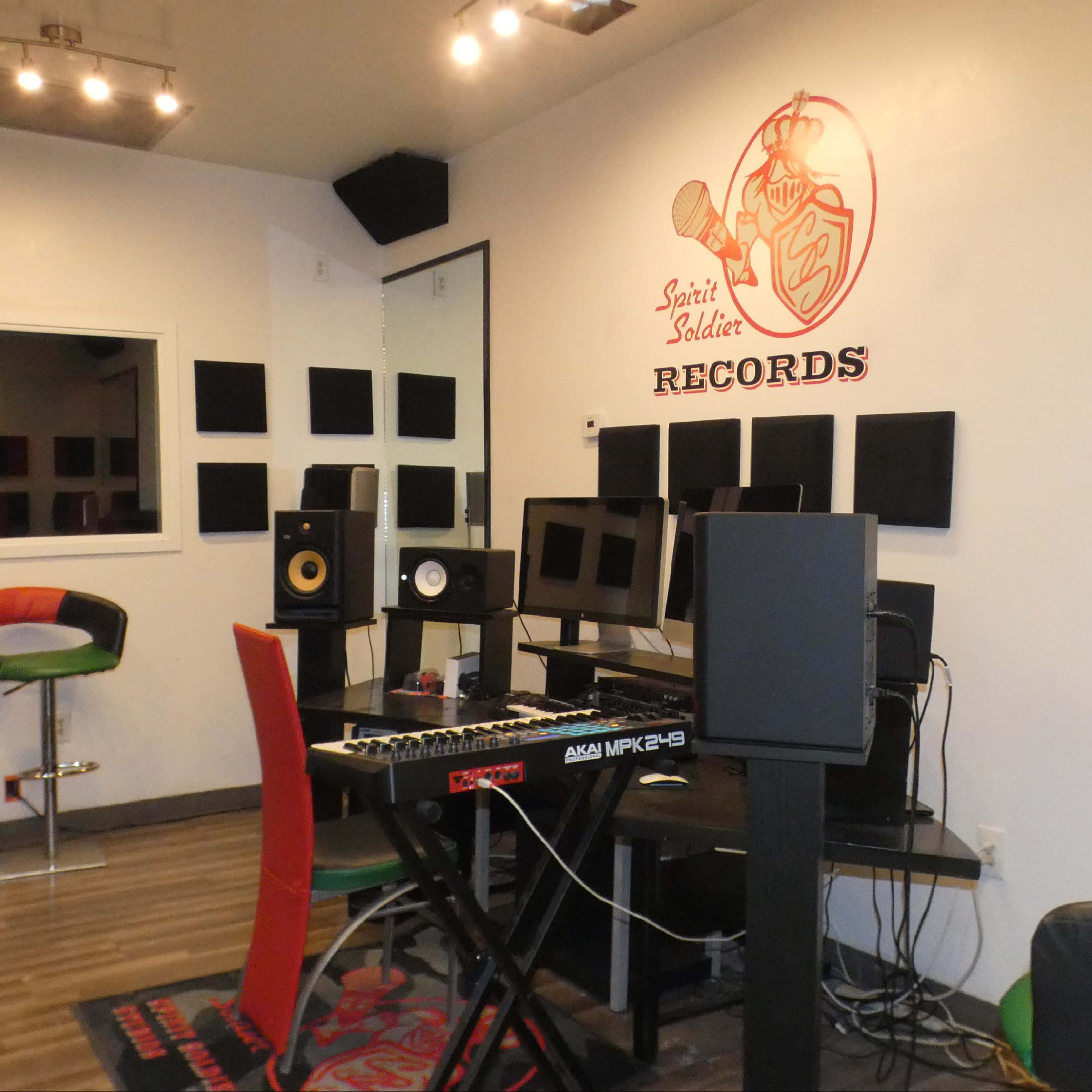 A small recording studio with a keyboard, monitors, and sound panels on the walls, branded with the logo "Sain't Muddah Records."