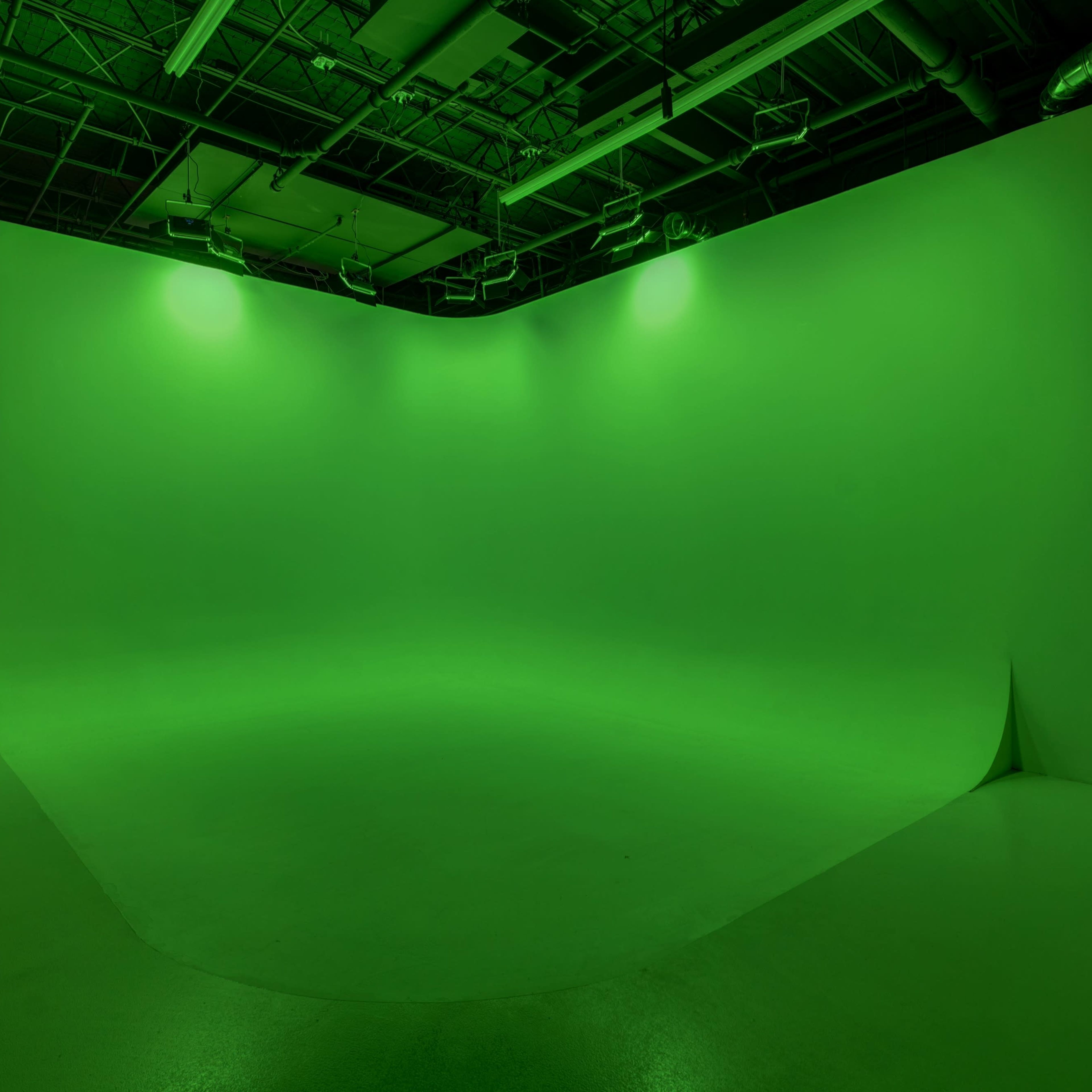 A green screen studio with a smooth, expansive green backdrop and artificial lighting.