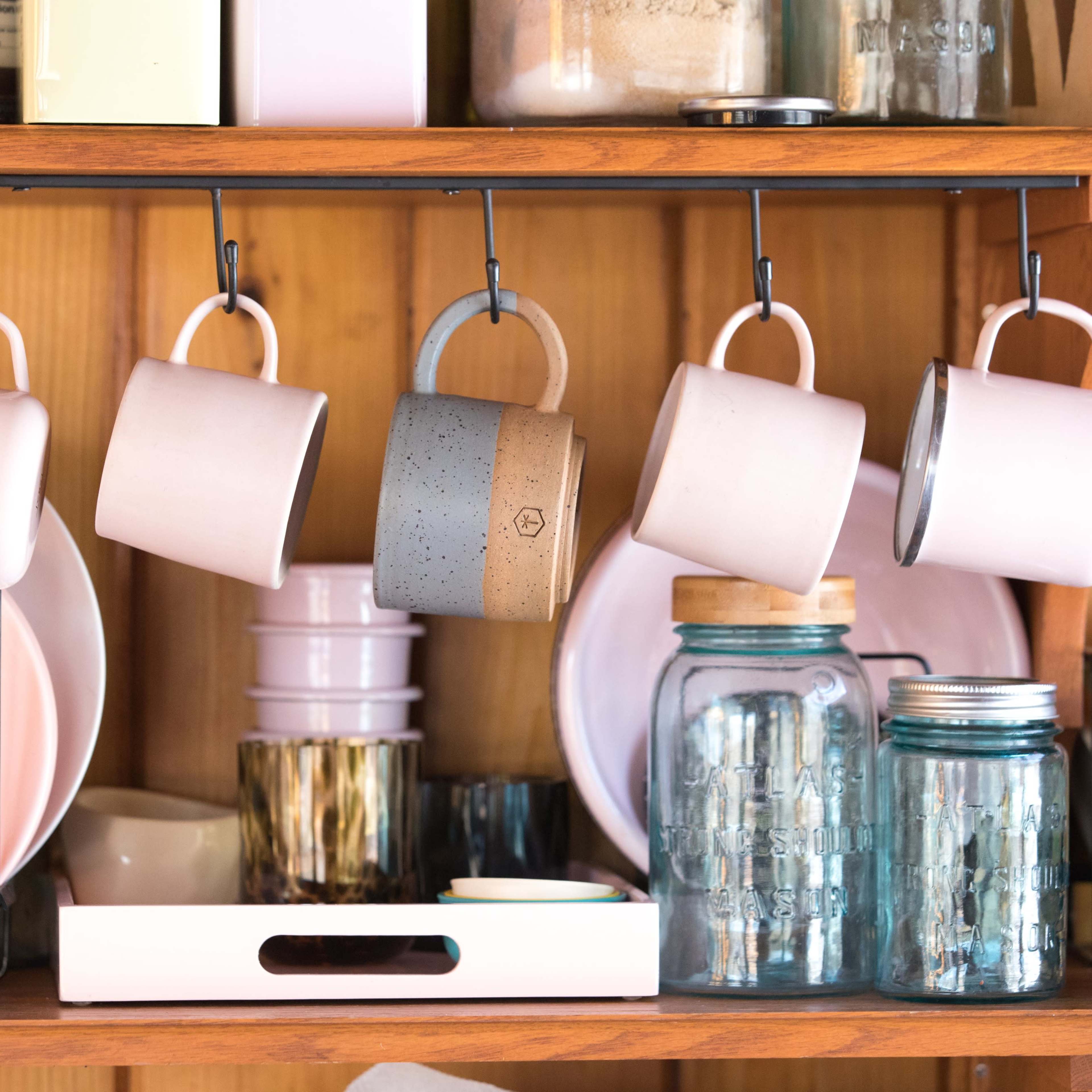 A variety of kitchen items, including hanging pots, glass jars, and a tray, organized on a shelf.
