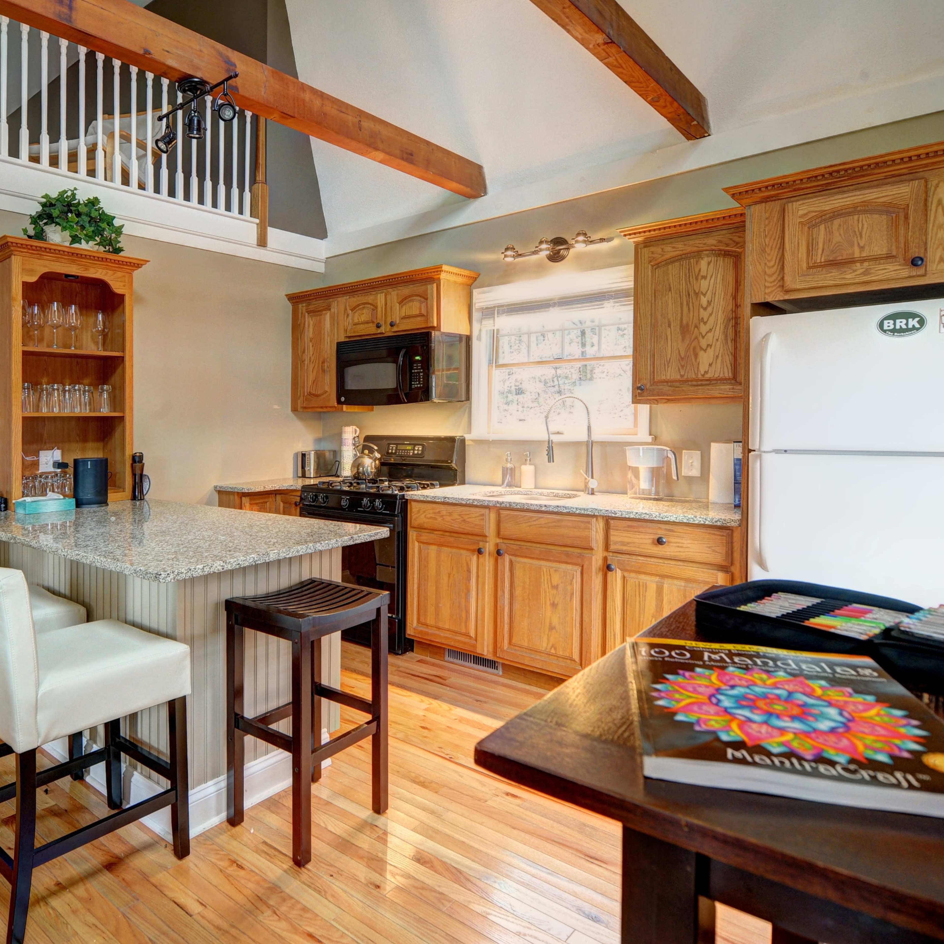 The kitchen features wooden cabinets, granite countertops, and a small breakfast bar with four stools.
