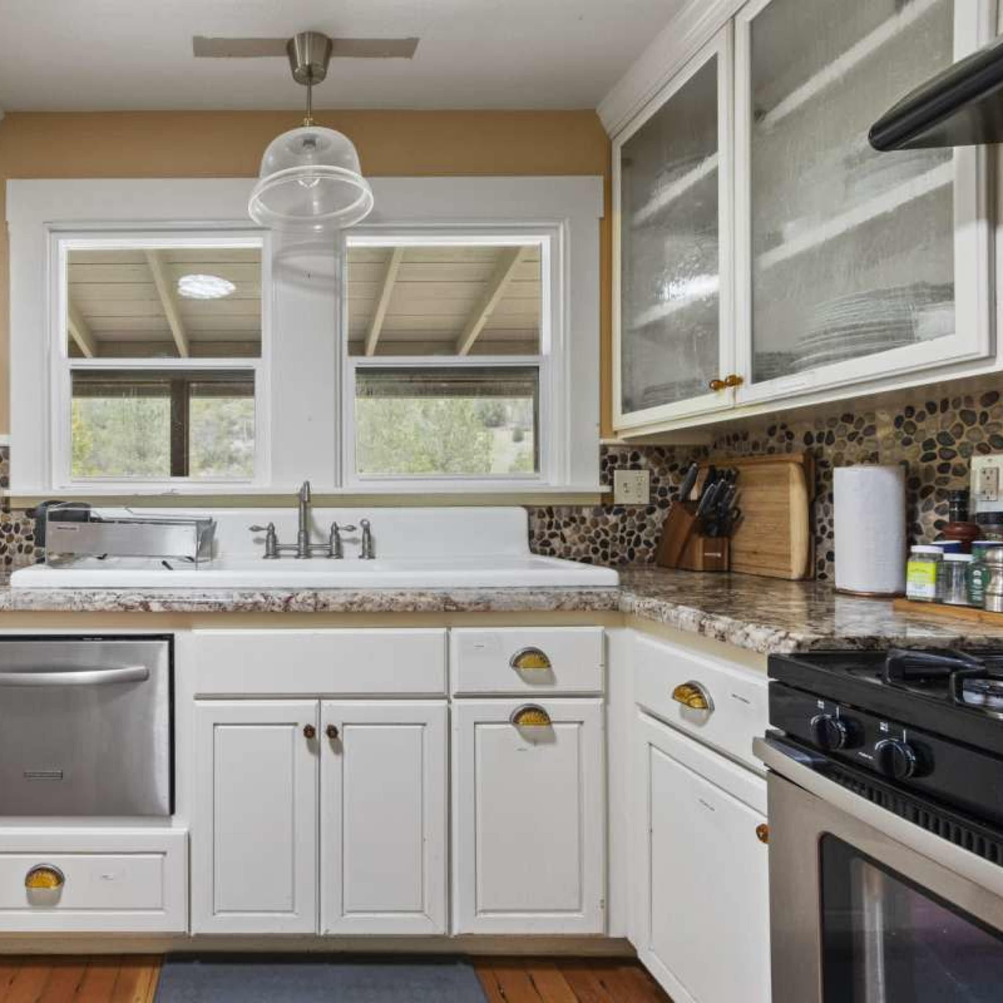 The kitchen features white cabinets, a double-basin sink, stainless steel appliances, and a window that allows natural light to enter.