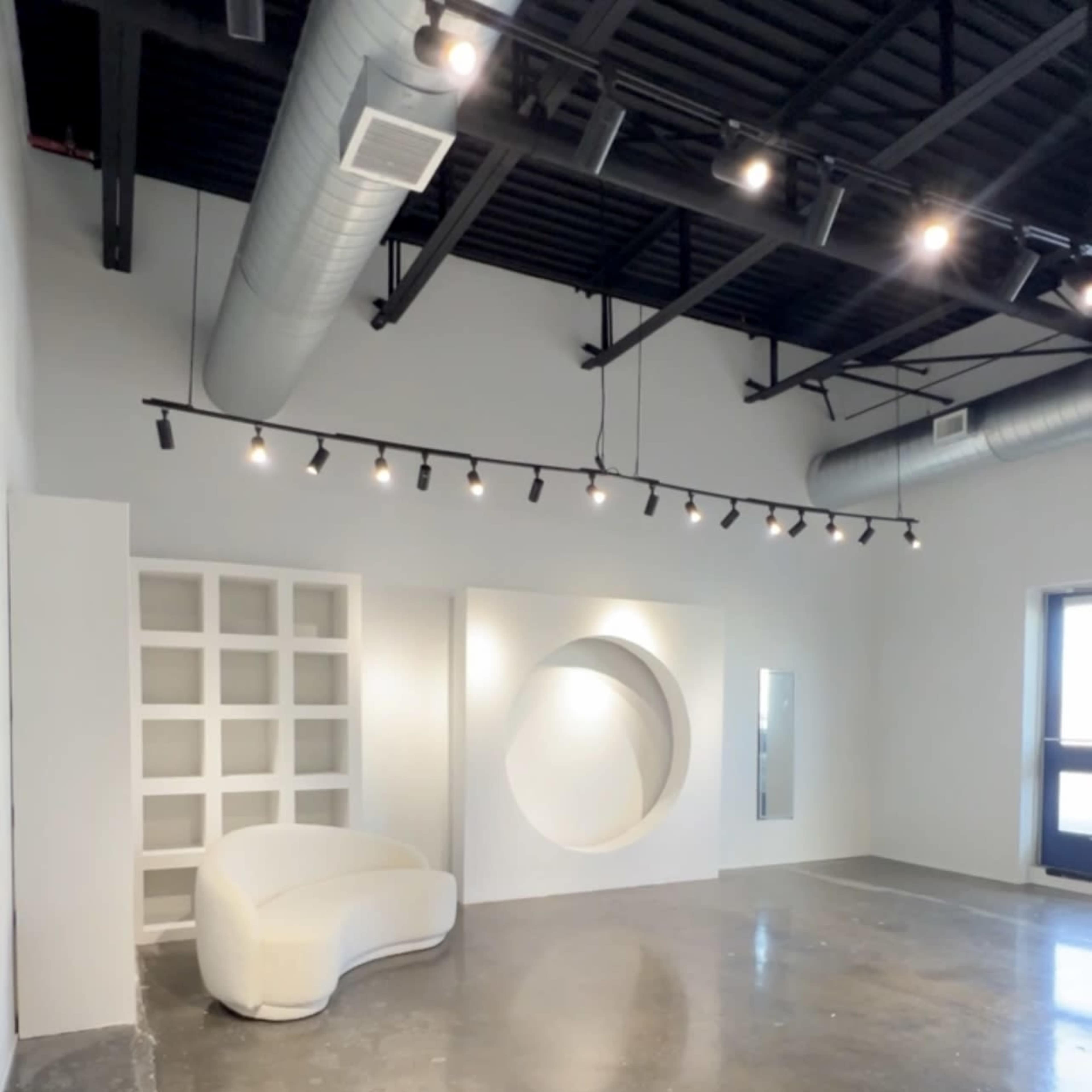 A spacious, minimalistic room with a white curved sofa, a circular wall feature, and large windows.