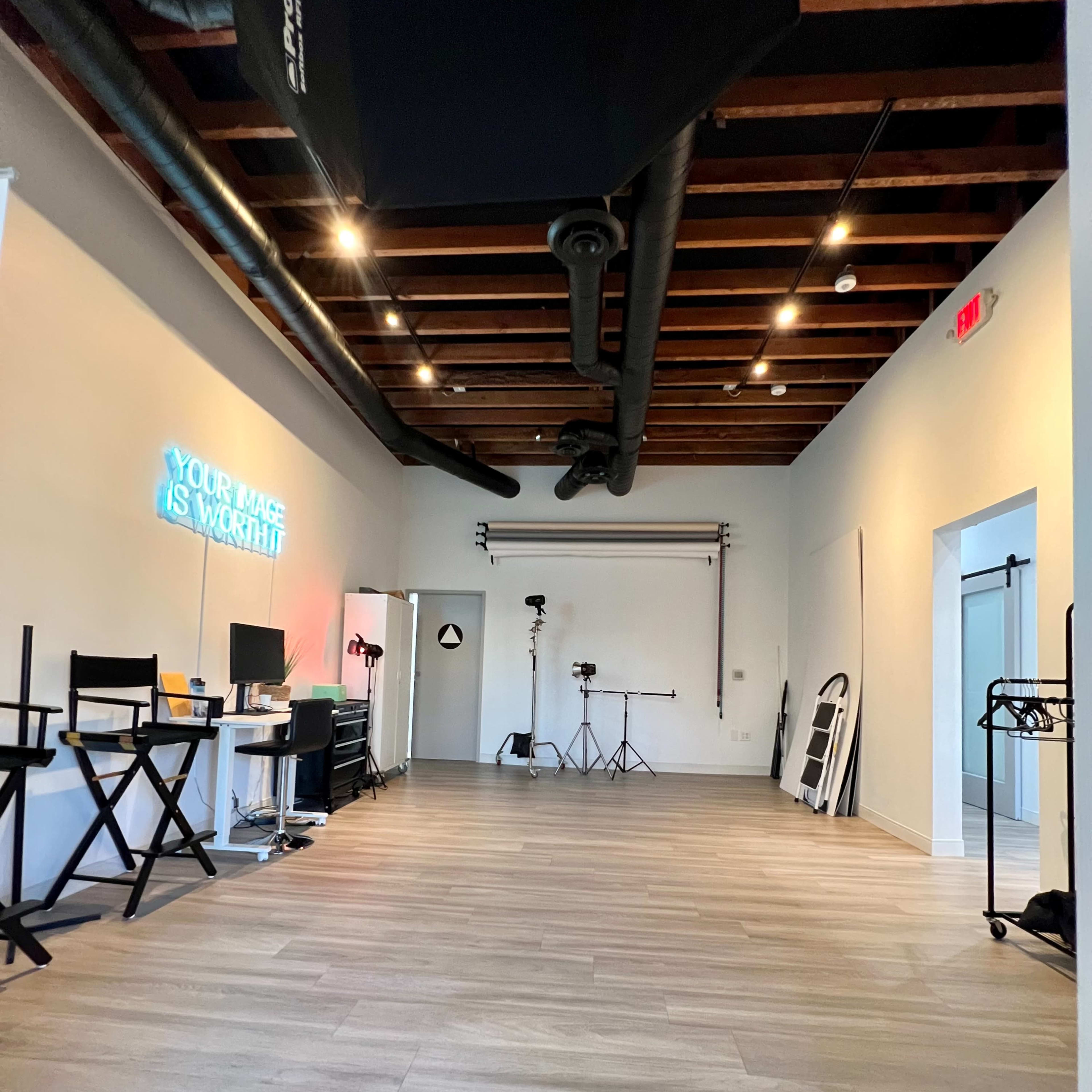 A spacious studio with wooden beams and a variety of equipment set up for photography.