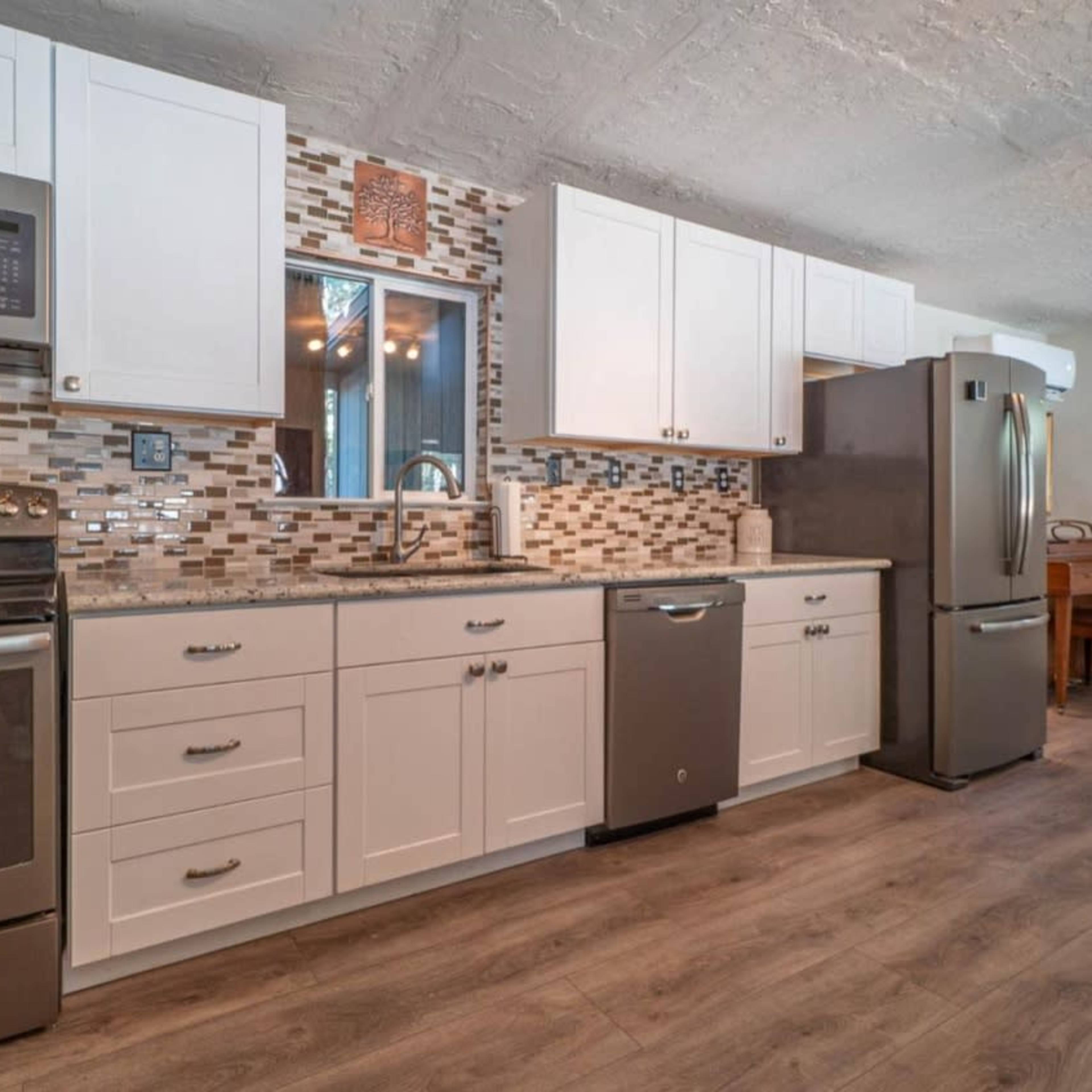 A modern kitchen featuring white cabinetry, stainless steel appliances, and a tiled backsplash.