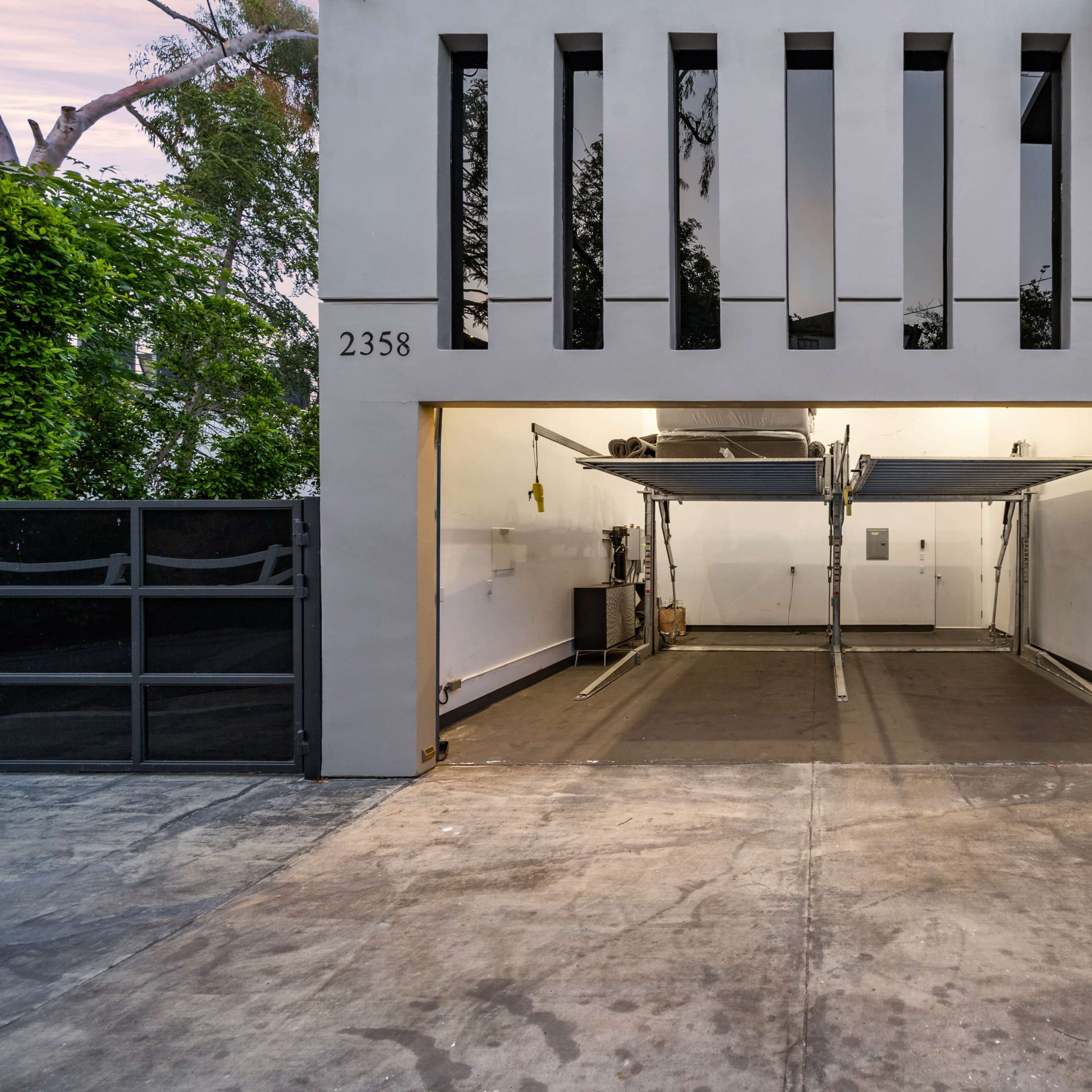 An empty garage with a smooth concrete floor and modern architecture featuring vertical window slits above the entrance.