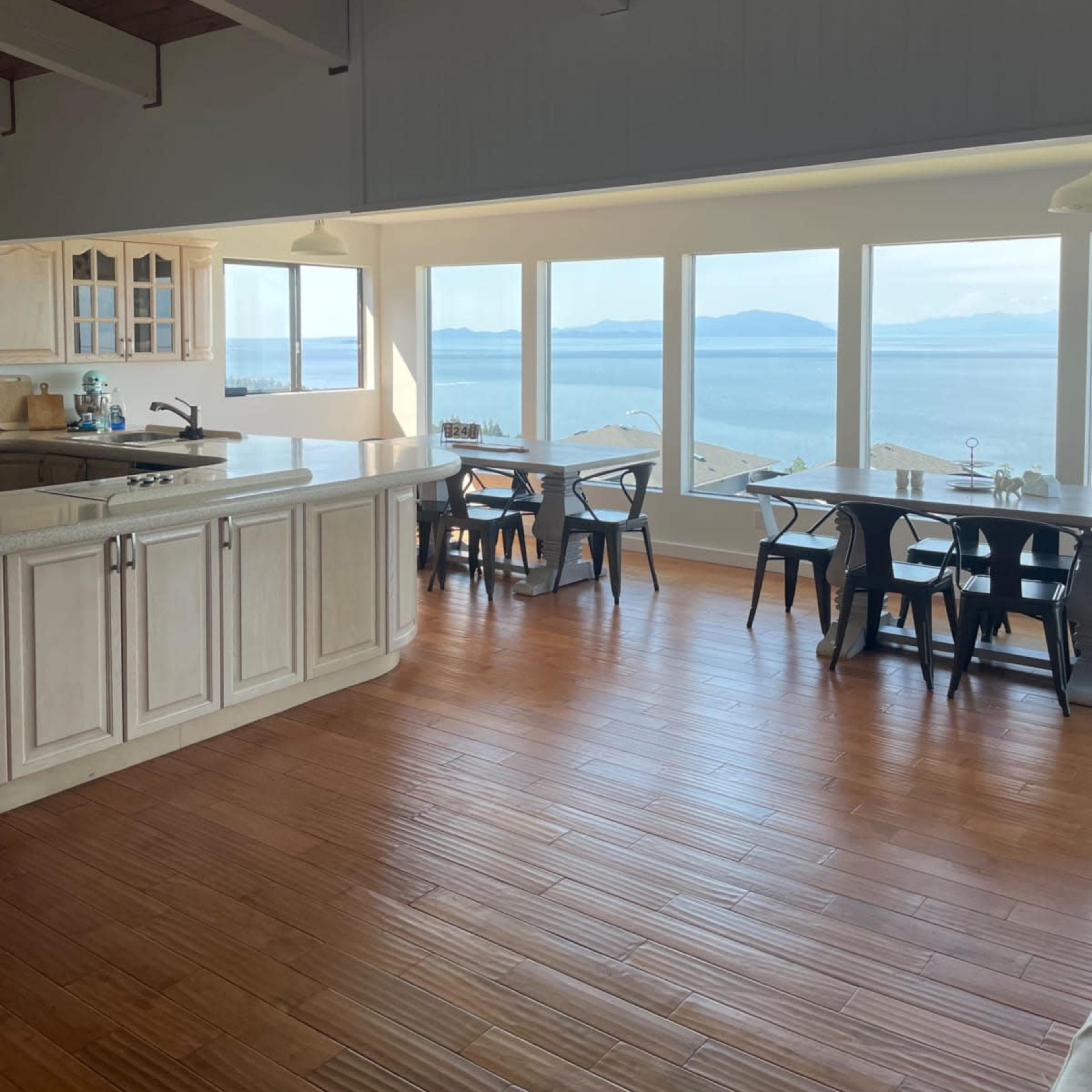 A spacious kitchen and dining area with large windows offering a view of the ocean and distant islands.
