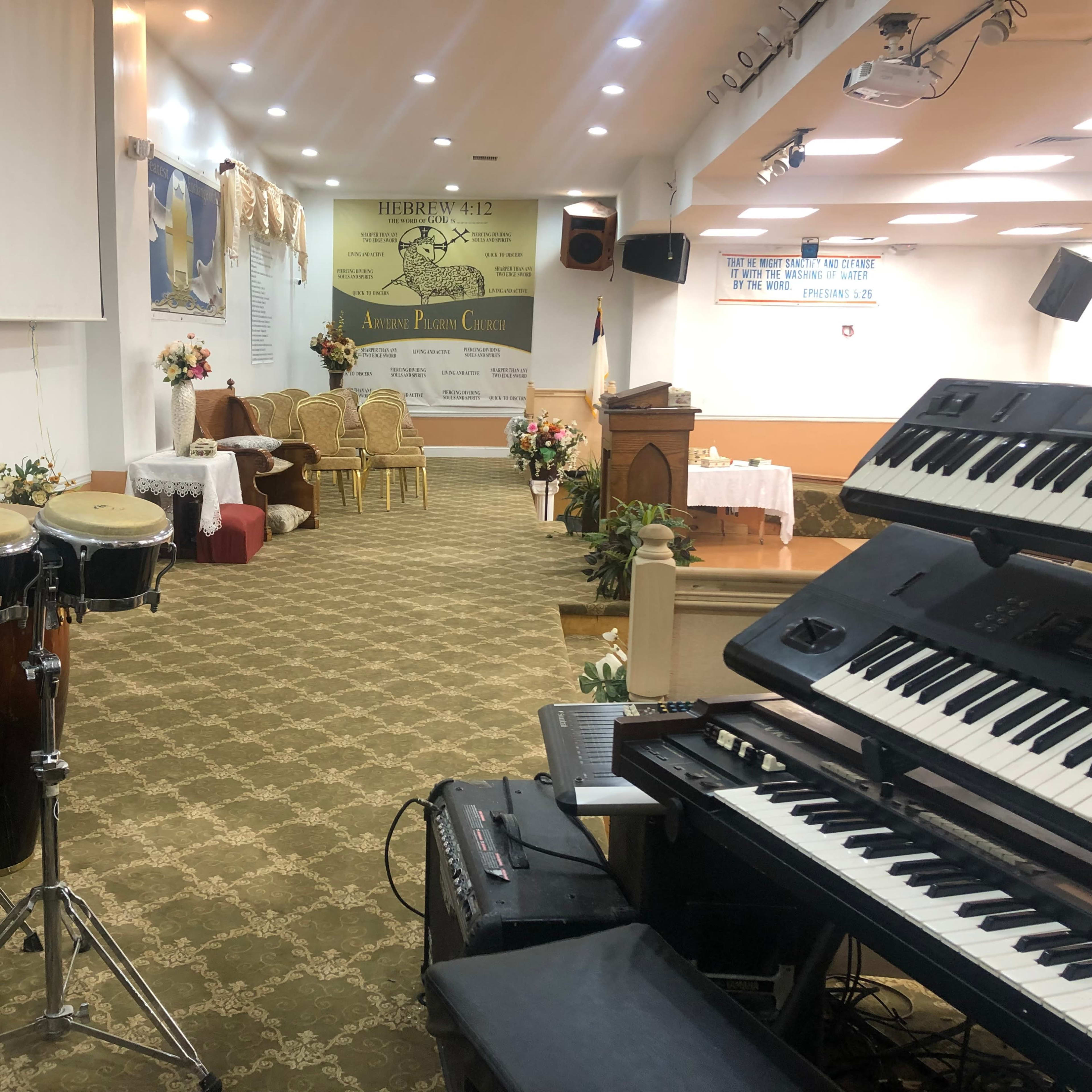 An interior of a church with musical instruments, a stage area, and decorative floral arrangements.