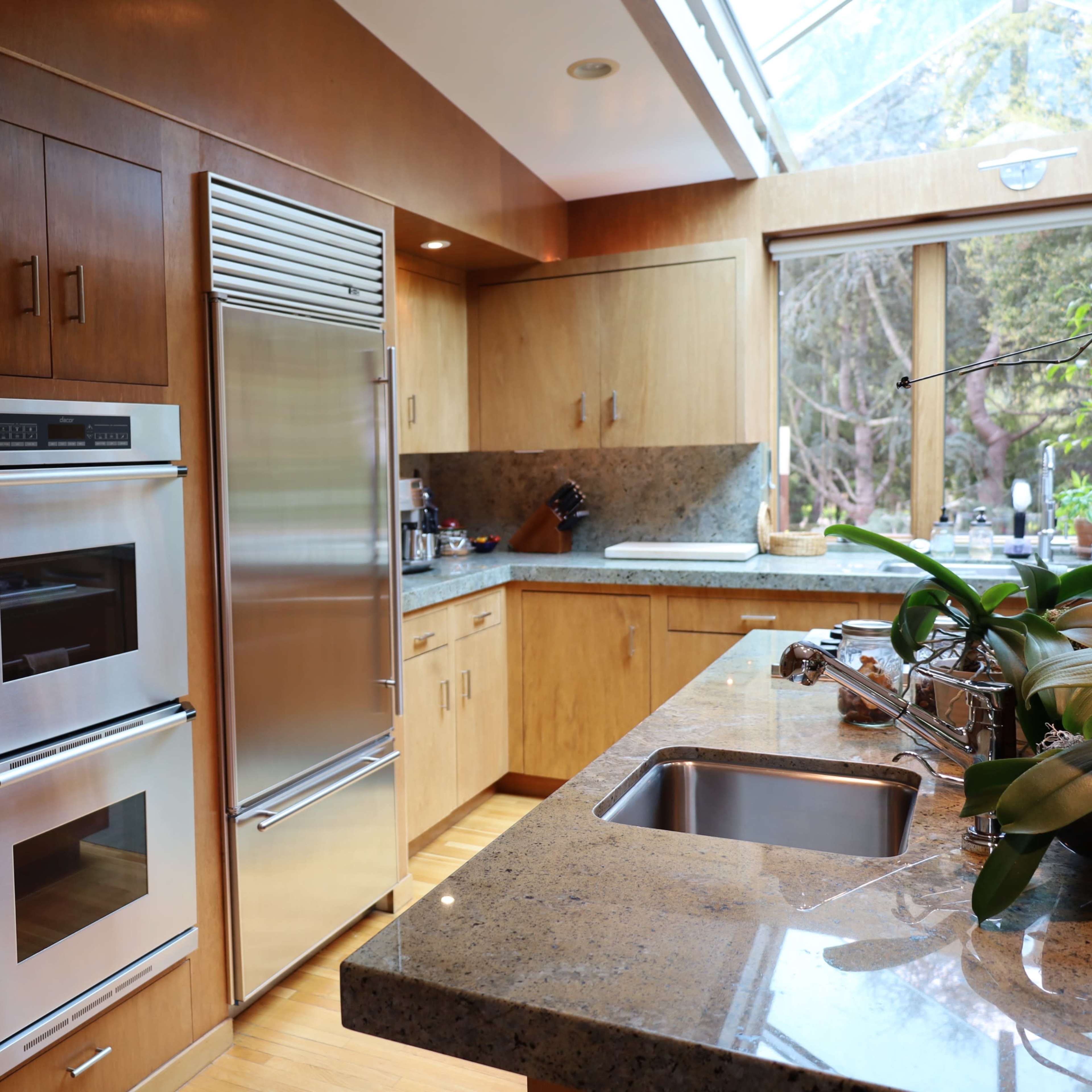 The kitchen features stainless steel appliances, wooden cabinetry, and a granite countertop with a sink.