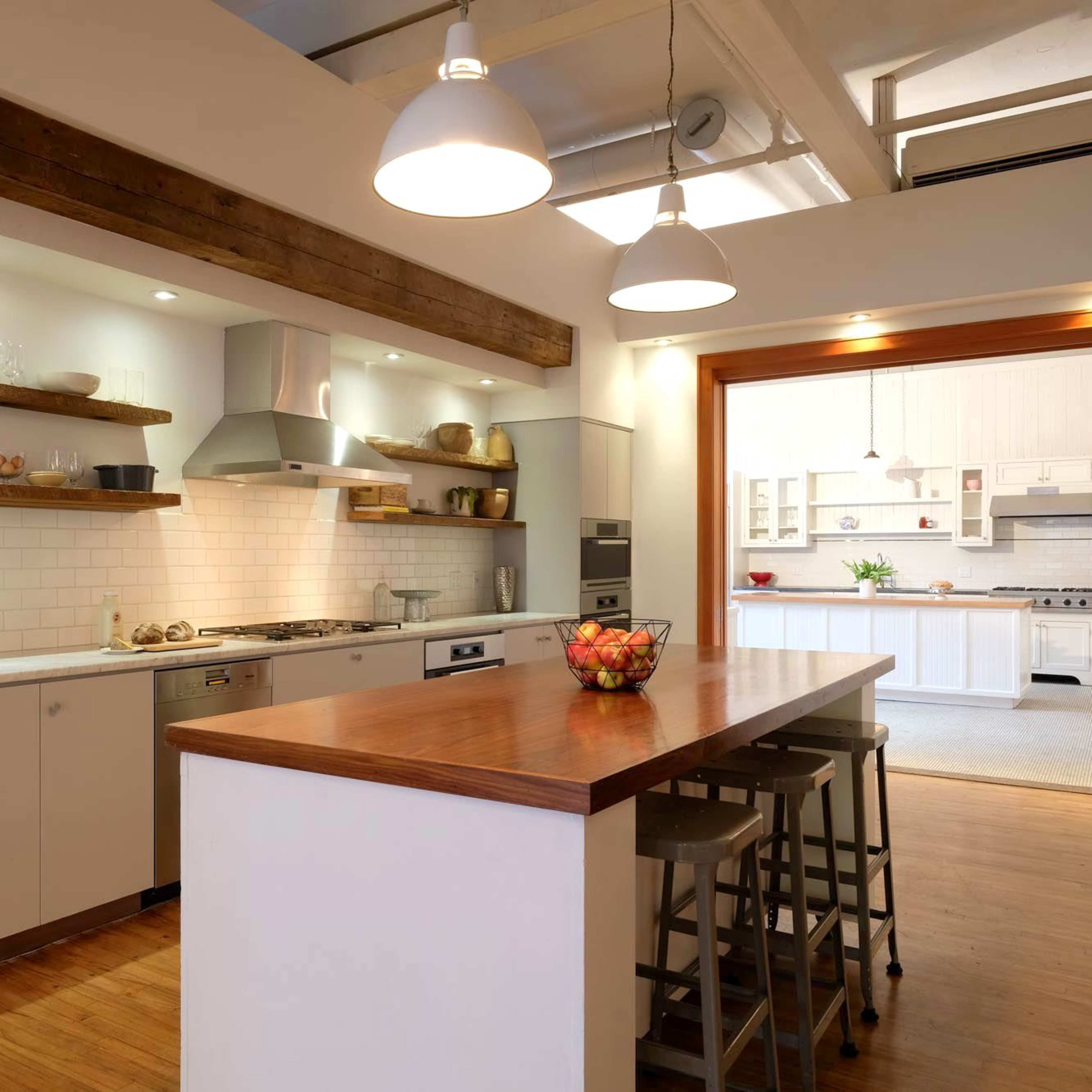 A modern kitchen with wooden shelves, stainless steel appliances, and an island with bar stools.