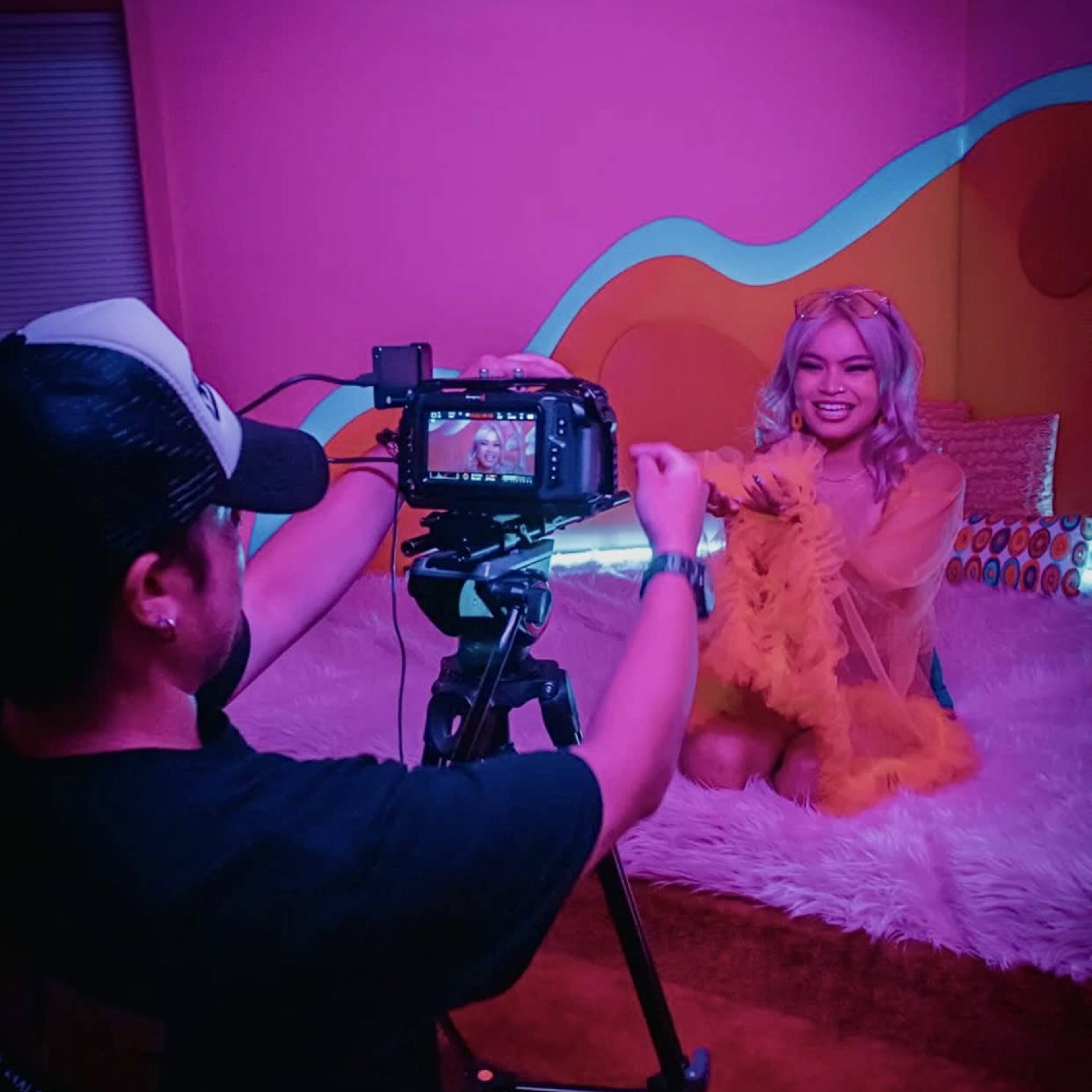 A photographer captures a subject in a brightly colored studio, featuring a fluffy backdrop and vibrant decor.