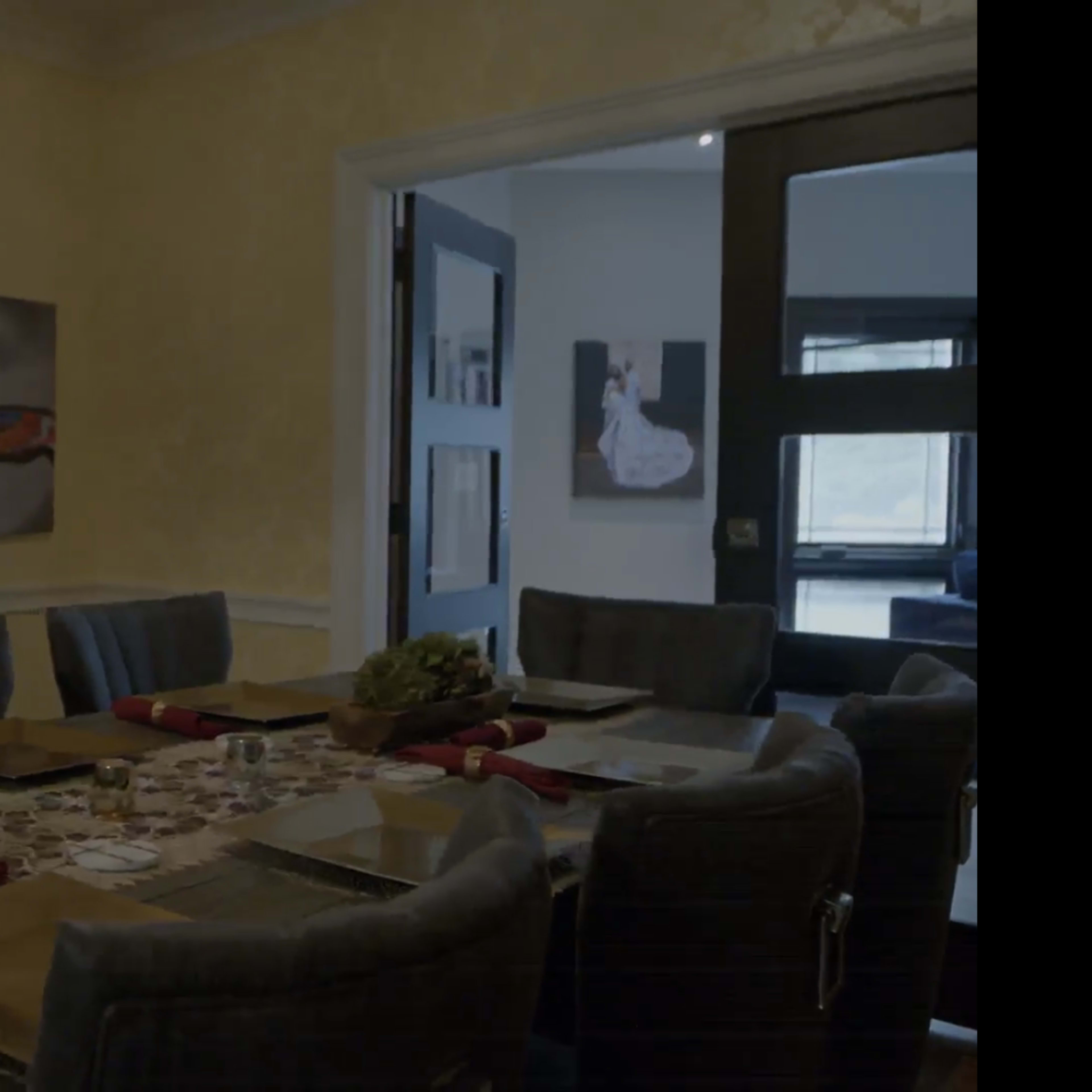 A dining room features a long table set for a meal, adorned with decorative centerpieces and artwork on the walls.