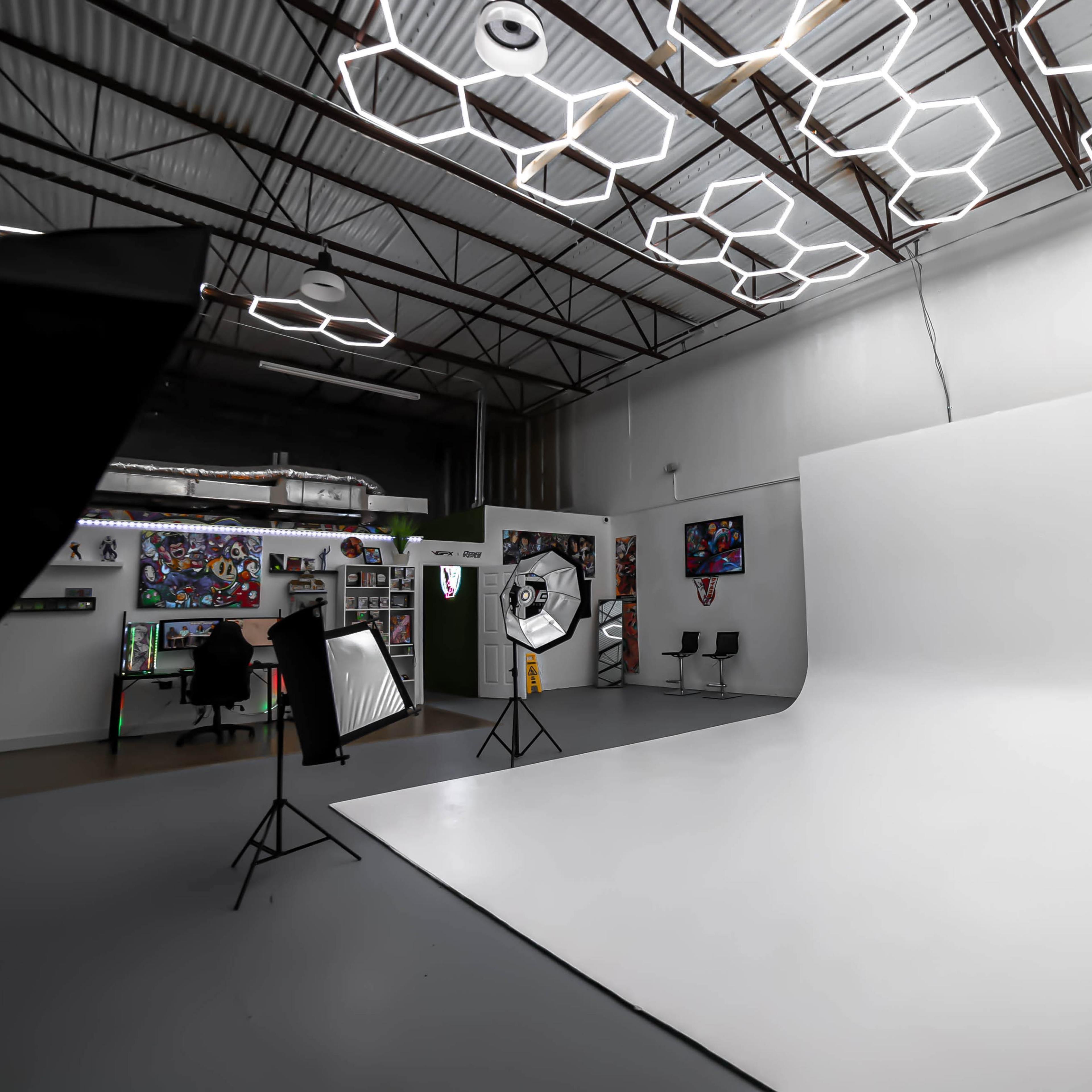 A photography studio featuring a large white backdrop, studio lights, and modern hexagonal ceiling fixtures.