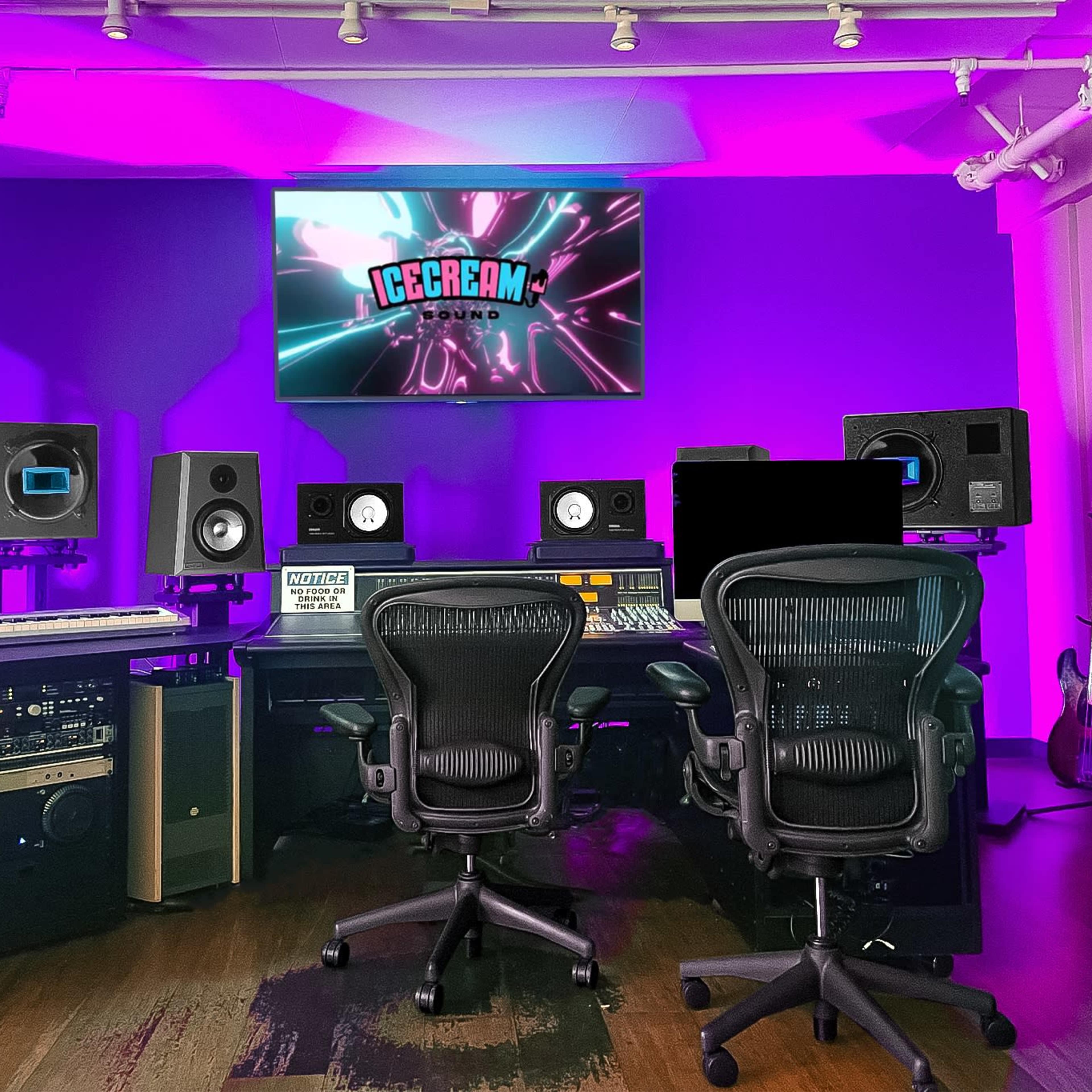 A modern music studio with a mixing console, two chairs, and audio equipment, illuminated by purple lighting.