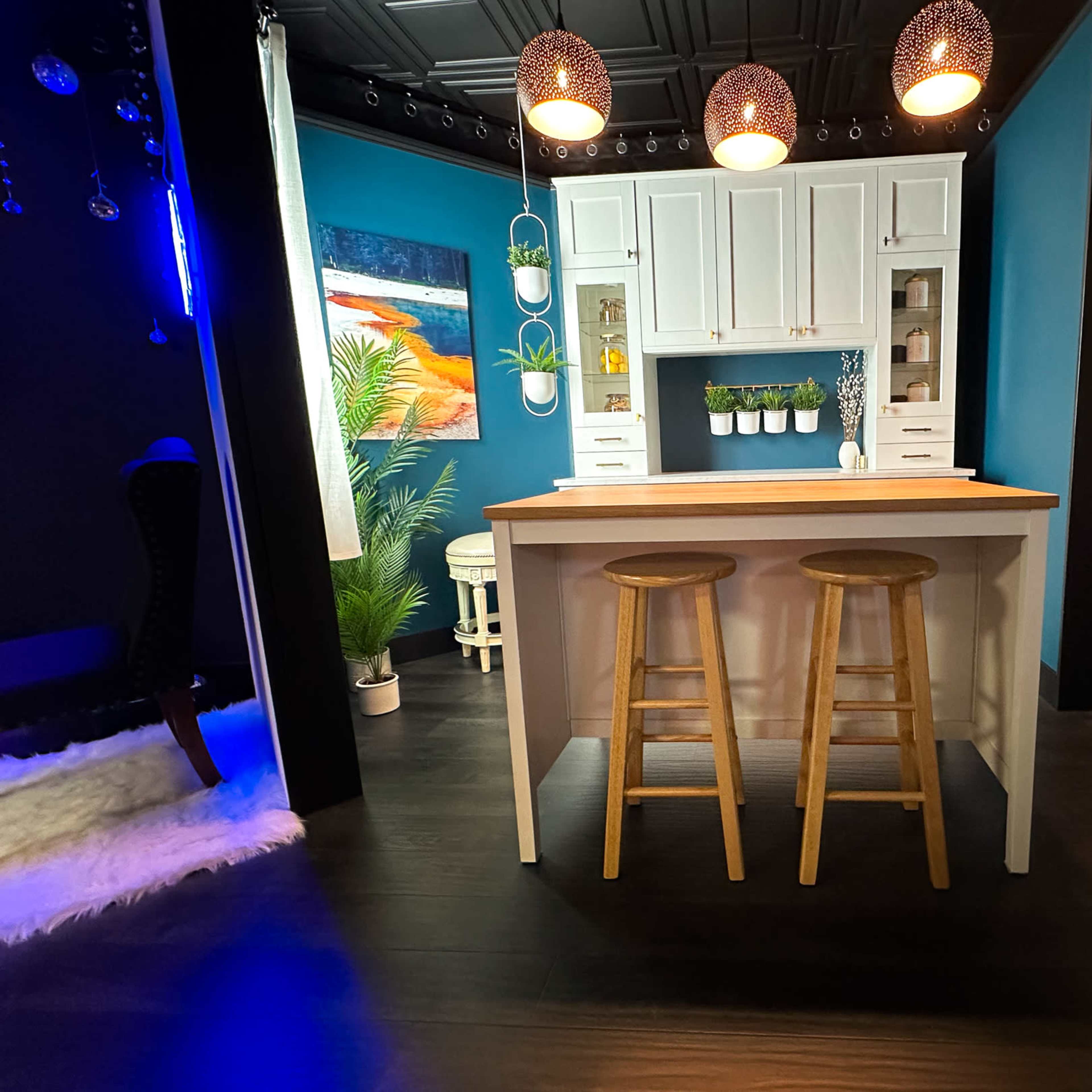A modern kitchen island with two wooden stools, surrounded by brightly colored walls and decorative elements.