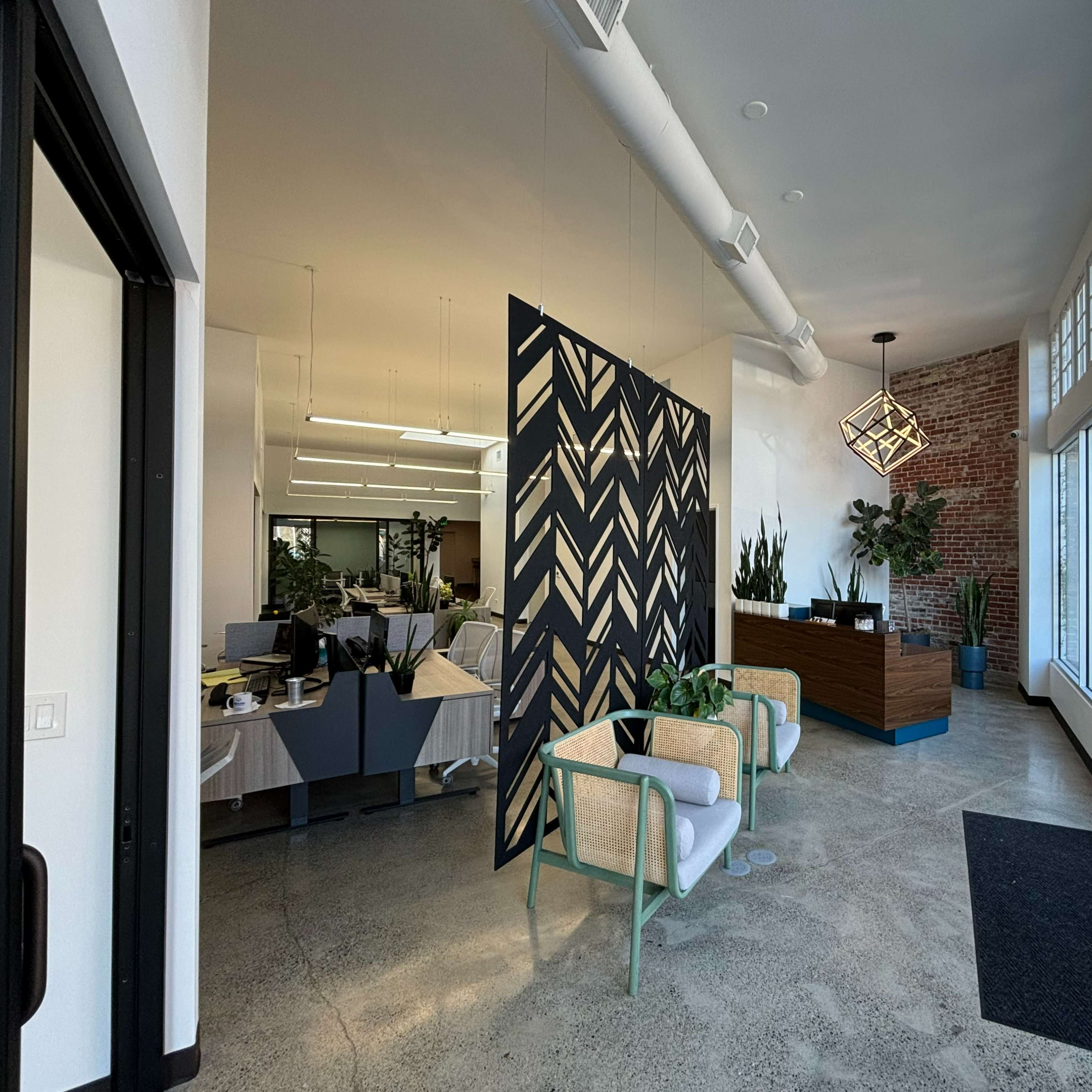 A modern office reception area with a decorative black and white partition, seating, and a front desk.