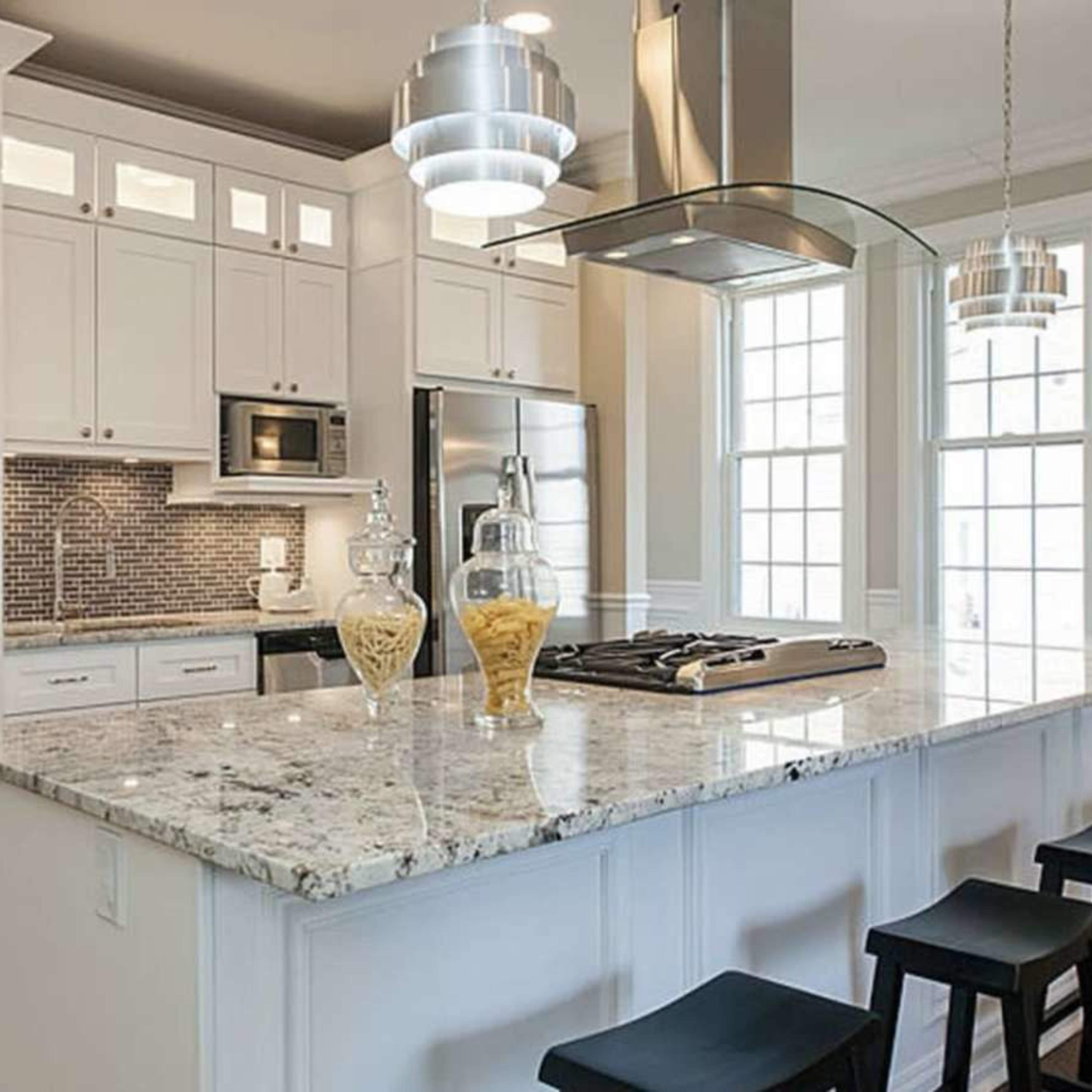 The kitchen features white cabinetry, a central island with a granite countertop, and modern stainless steel appliances.