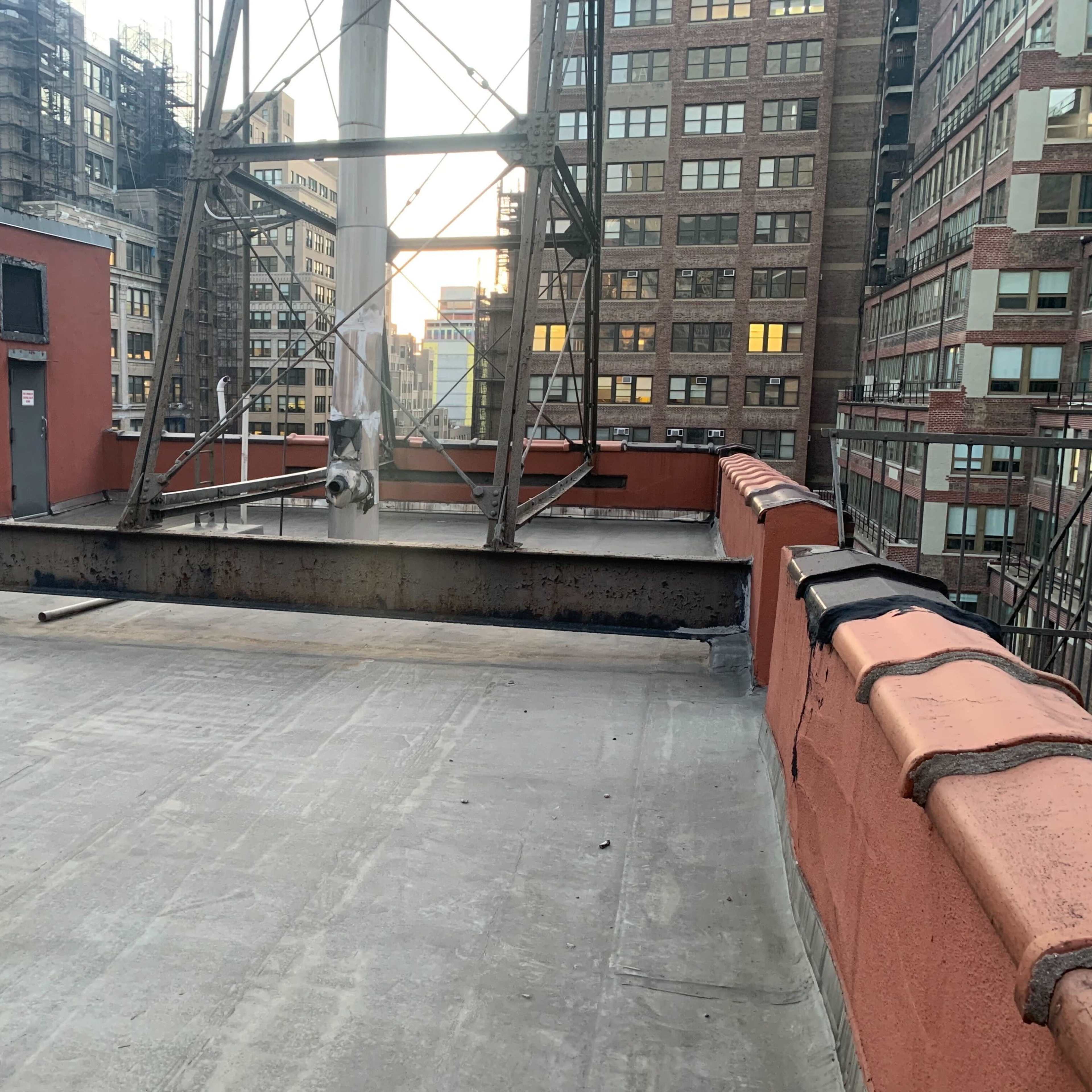 A metal framework stands on a rooftop, surrounded by tall buildings and a clear sky at dusk.