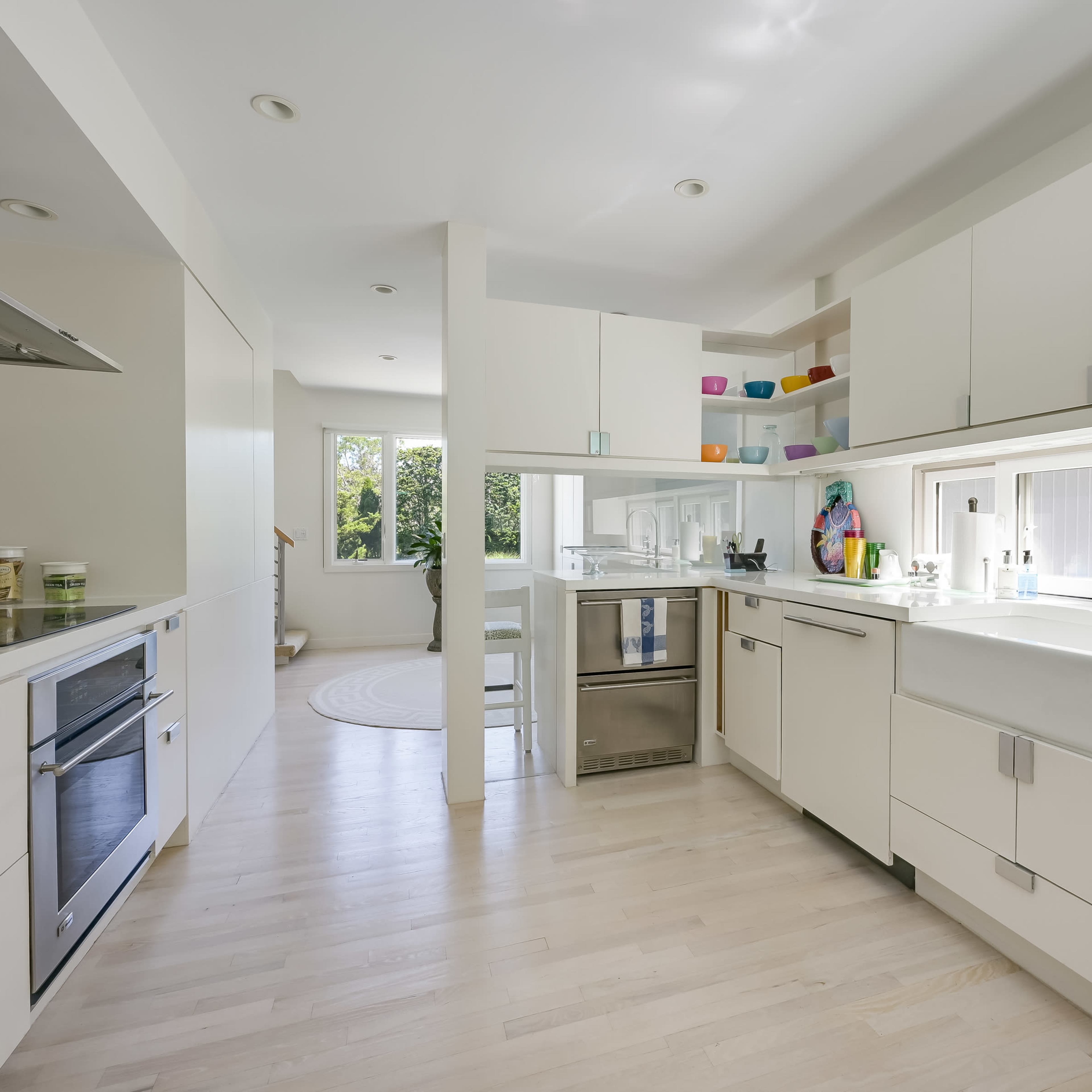 A modern kitchen with white cabinetry, a central island, and large windows that provide natural light.