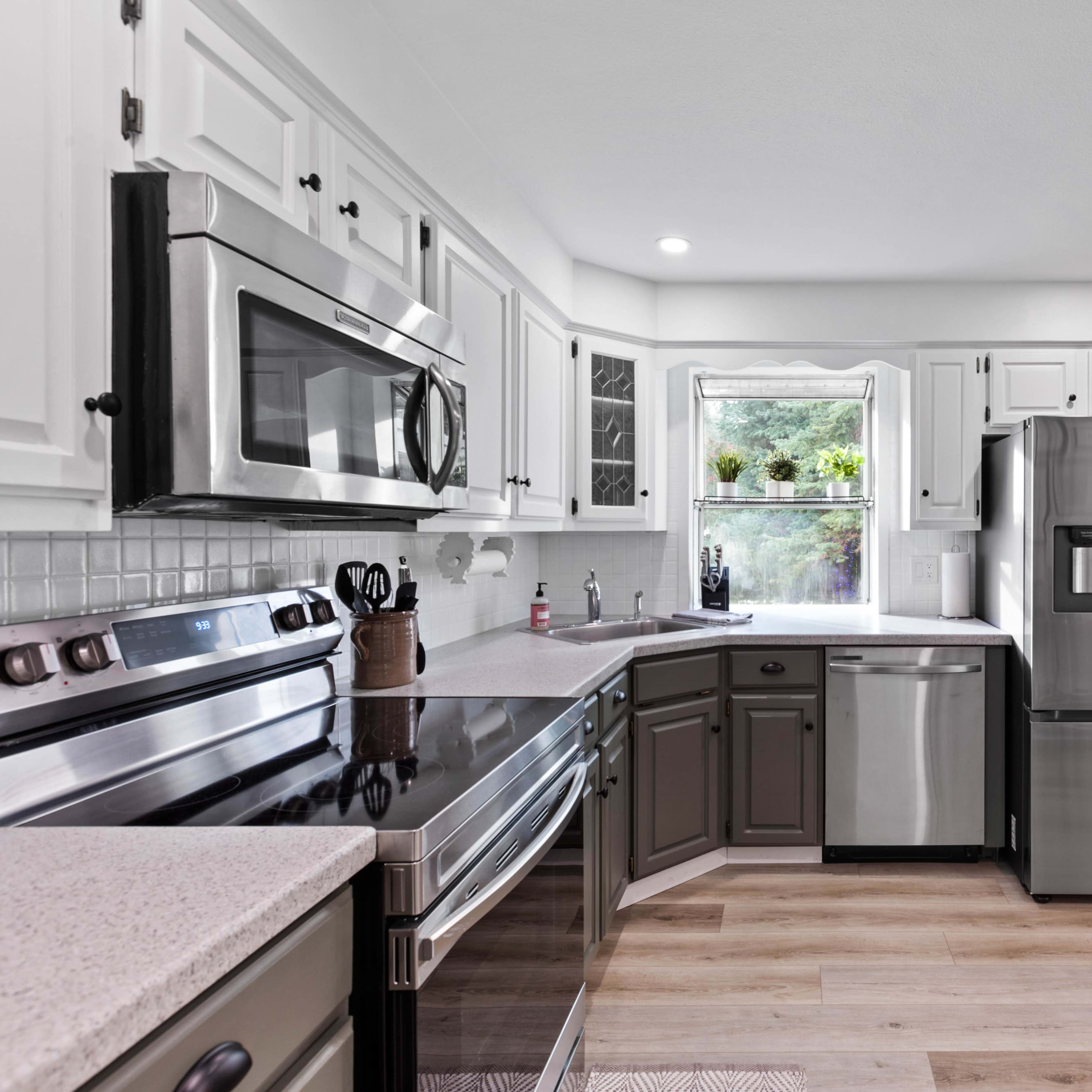 A modern kitchen featuring stainless steel appliances, white cabinets, and a dark countertop.