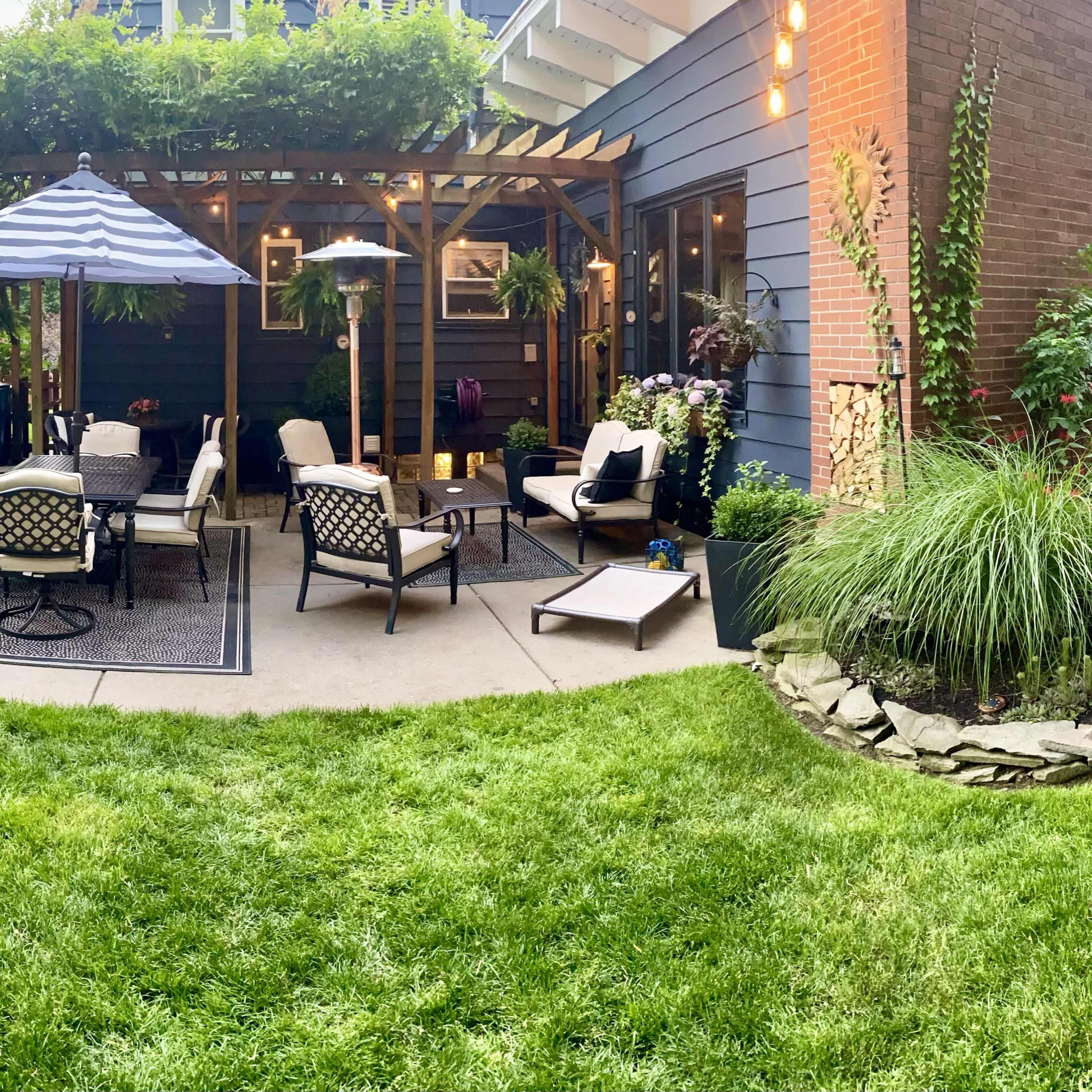 A patio area with seating and a canopy, surrounded by greenery and plants.