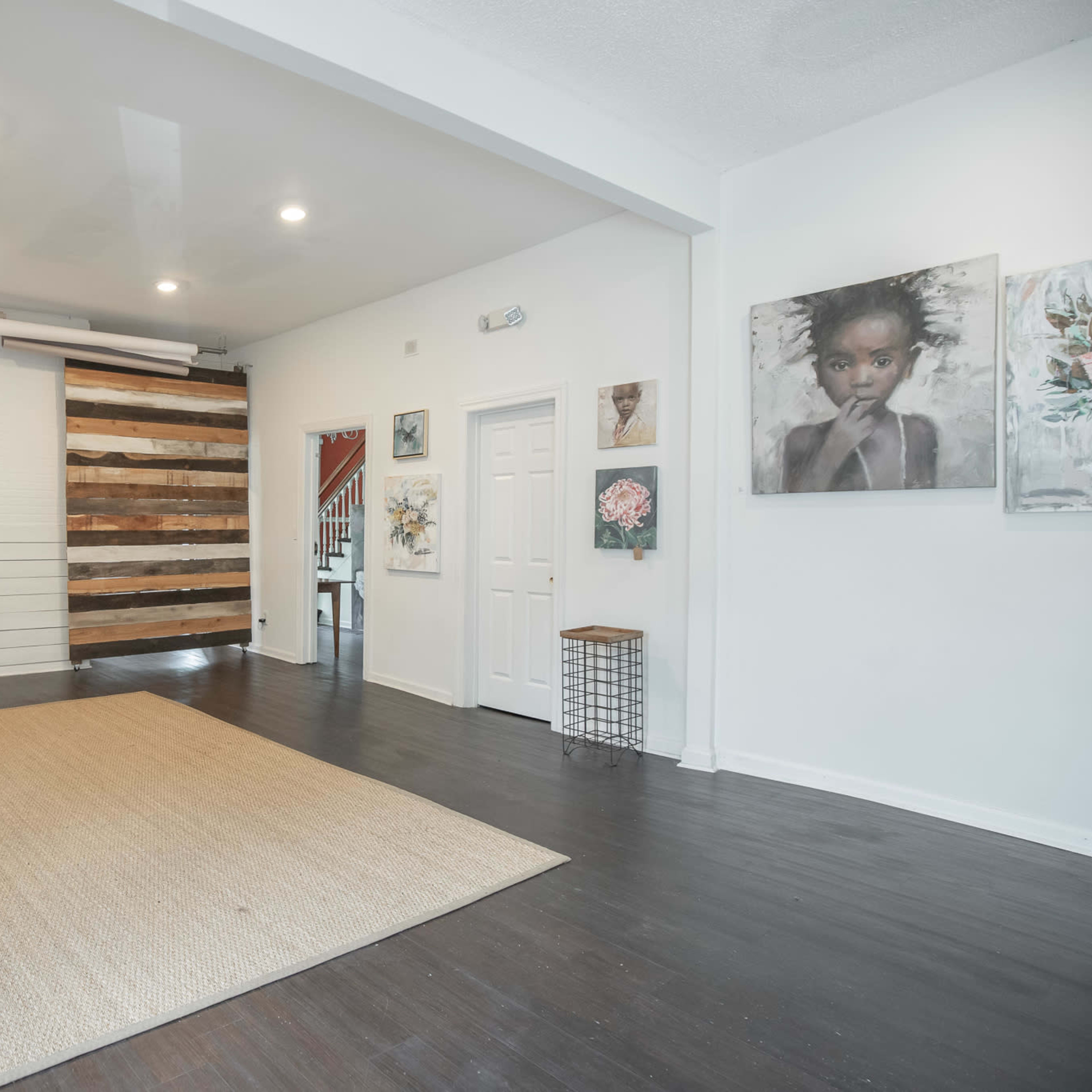 The room features a wooden floor, white walls, and a wall with a rustic wooden panel design, illuminated by overhead lights.