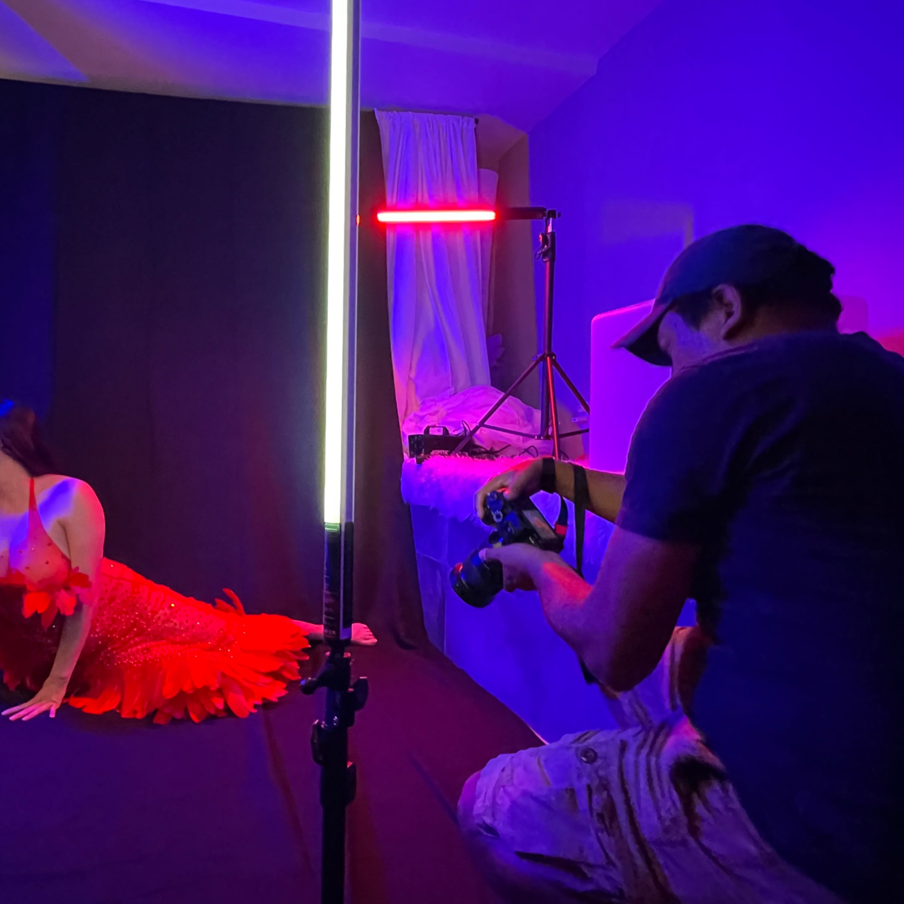 A woman in a red feathered dress poses in front of a mirror while a photographer captures the scene.