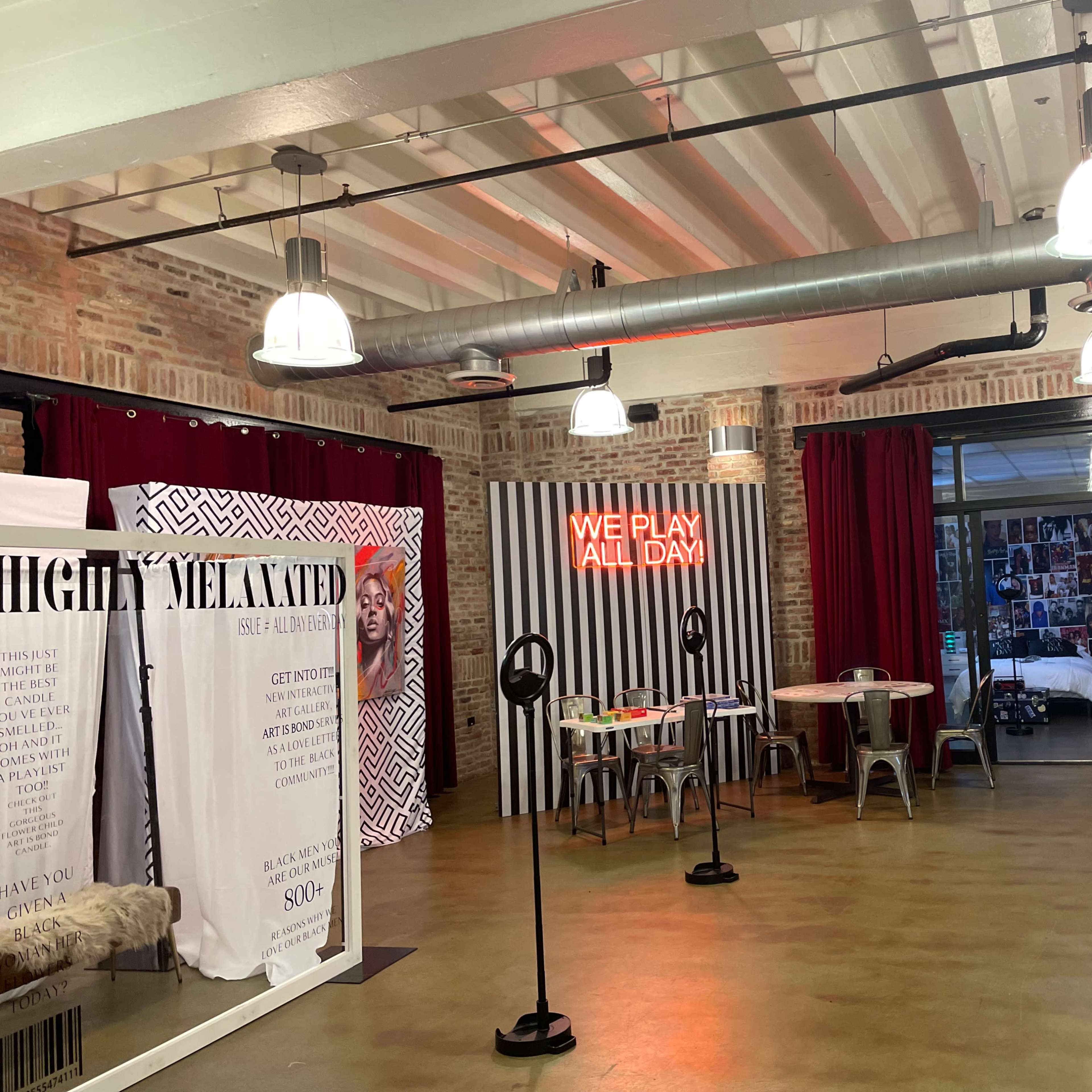 An interior space featuring brick walls, industrial lighting, red curtains, and a mix of seating areas with decorative elements and text displays.
